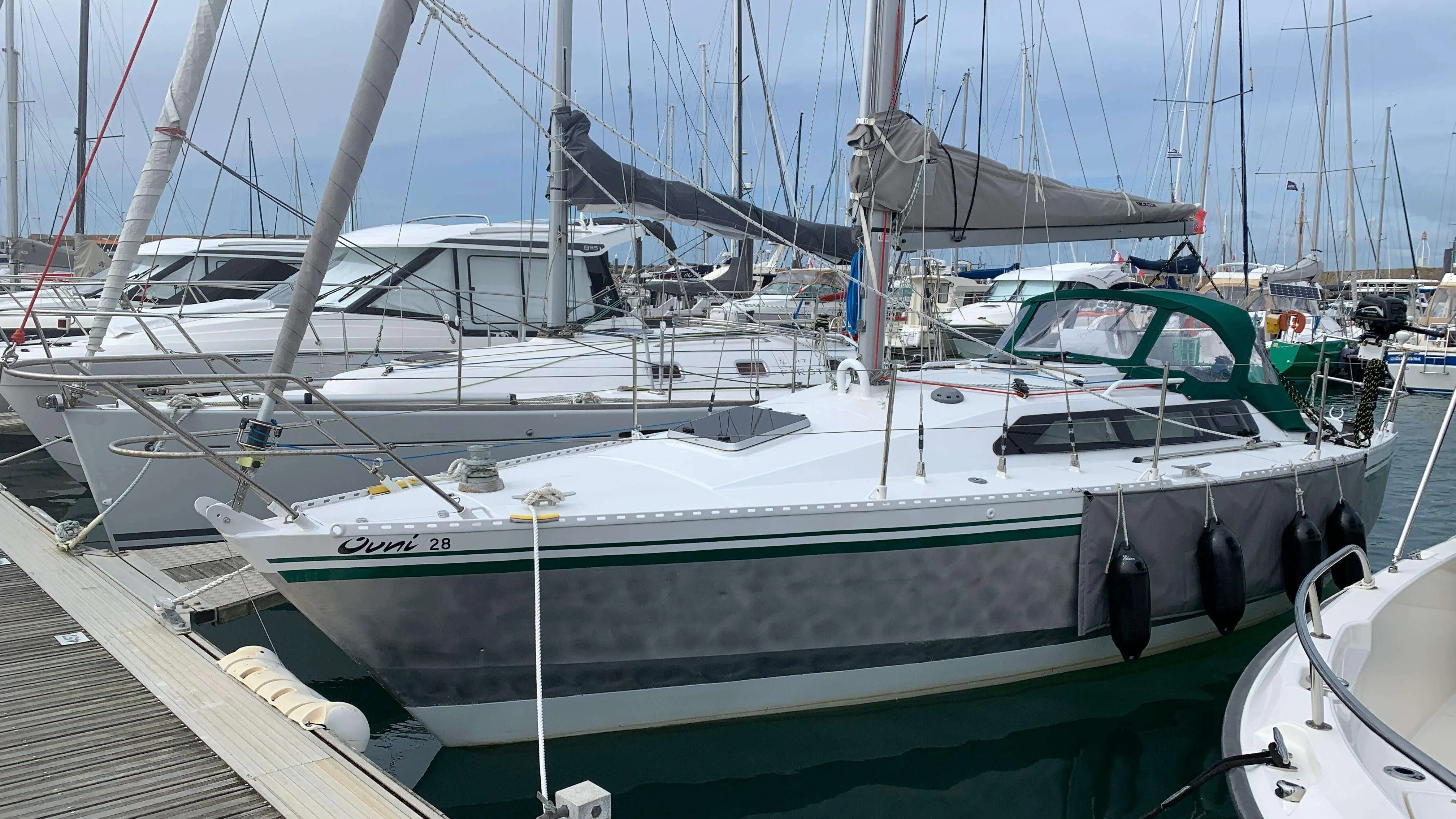 Alubat Ovni 28 — Voilier blanc à l’amarrage, vu de trois quarts dans un port de plaisance.