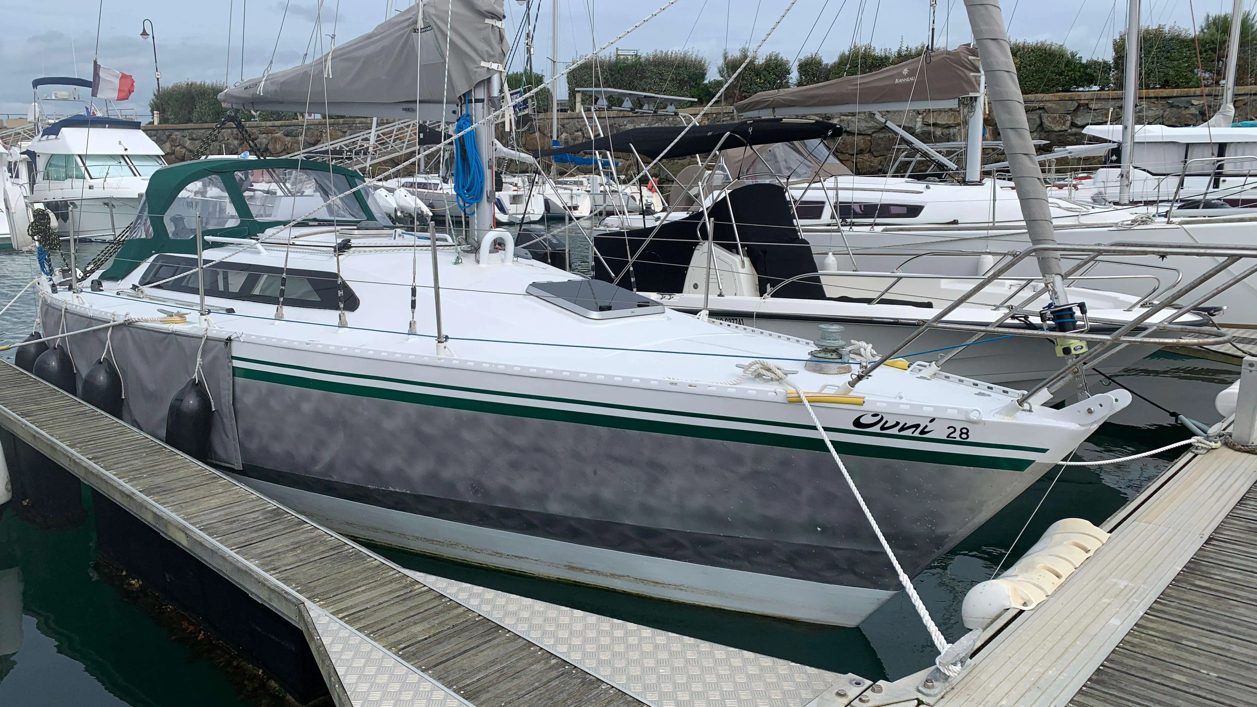 Alubat Ovni 28 — Voilier blanc amarré dans un port, vu de profil entre les pontons.