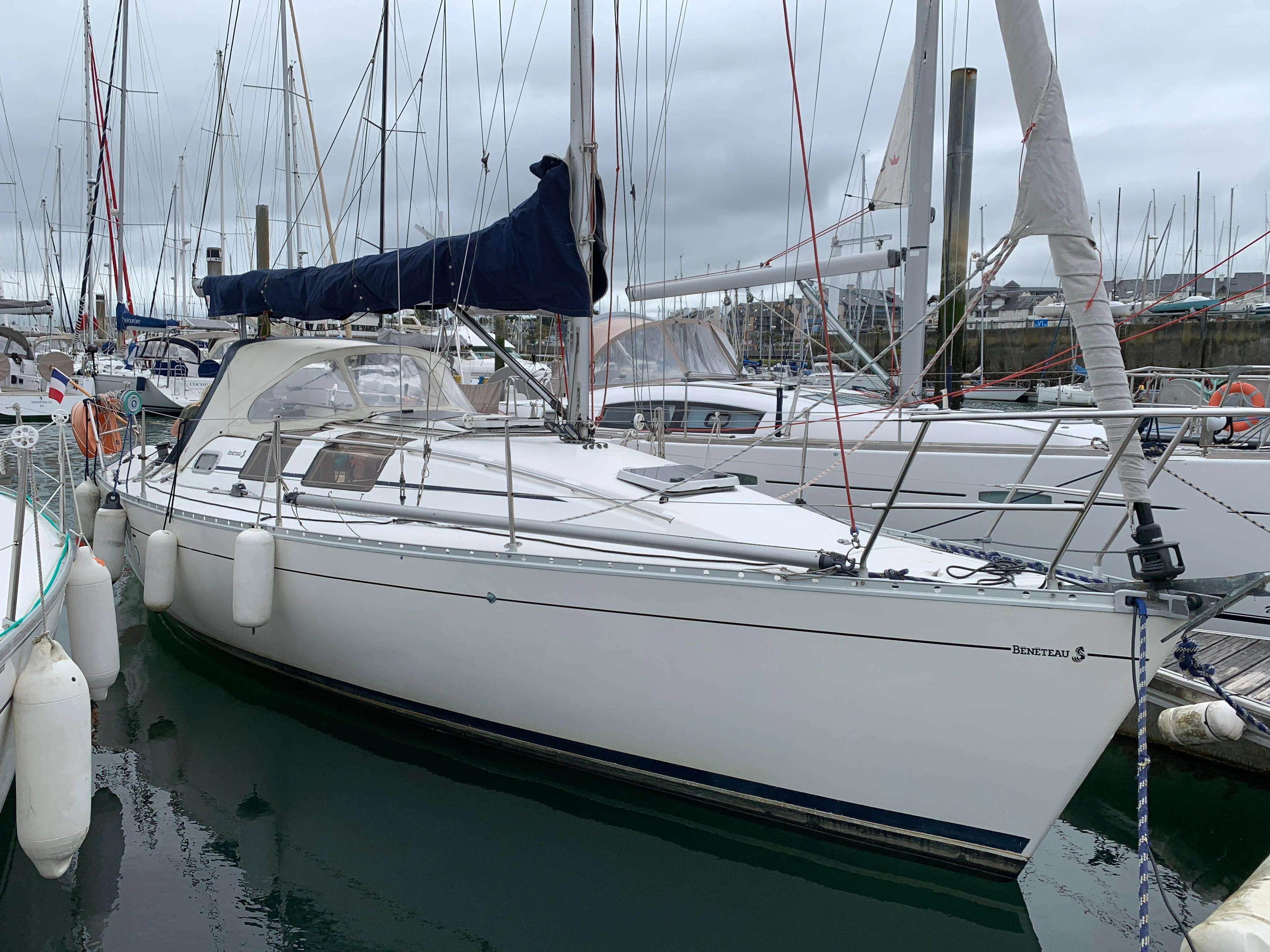 Beneteau First 32 — Voilier blanc amarré dans un port, vu de trois quarts tribord.