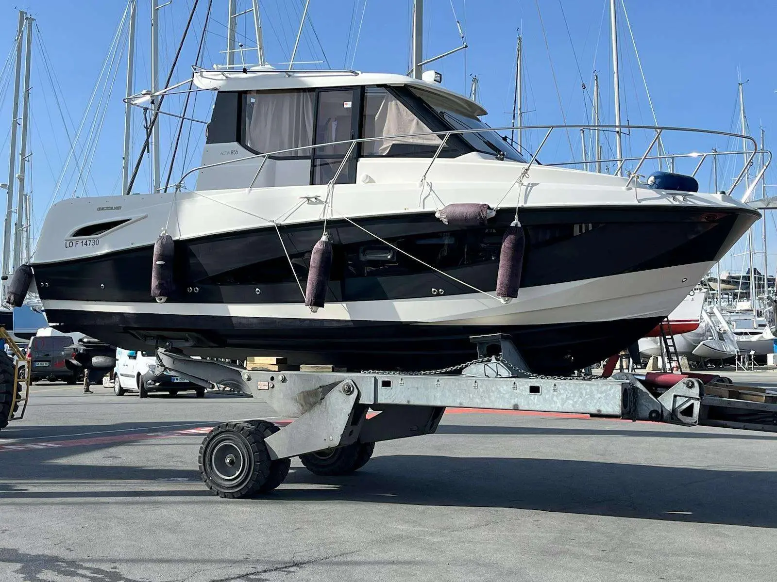 Quicksilver Activ 855 Weekend — Bateau blanc et noir vu de profil, posé sur une remorque dans un port.