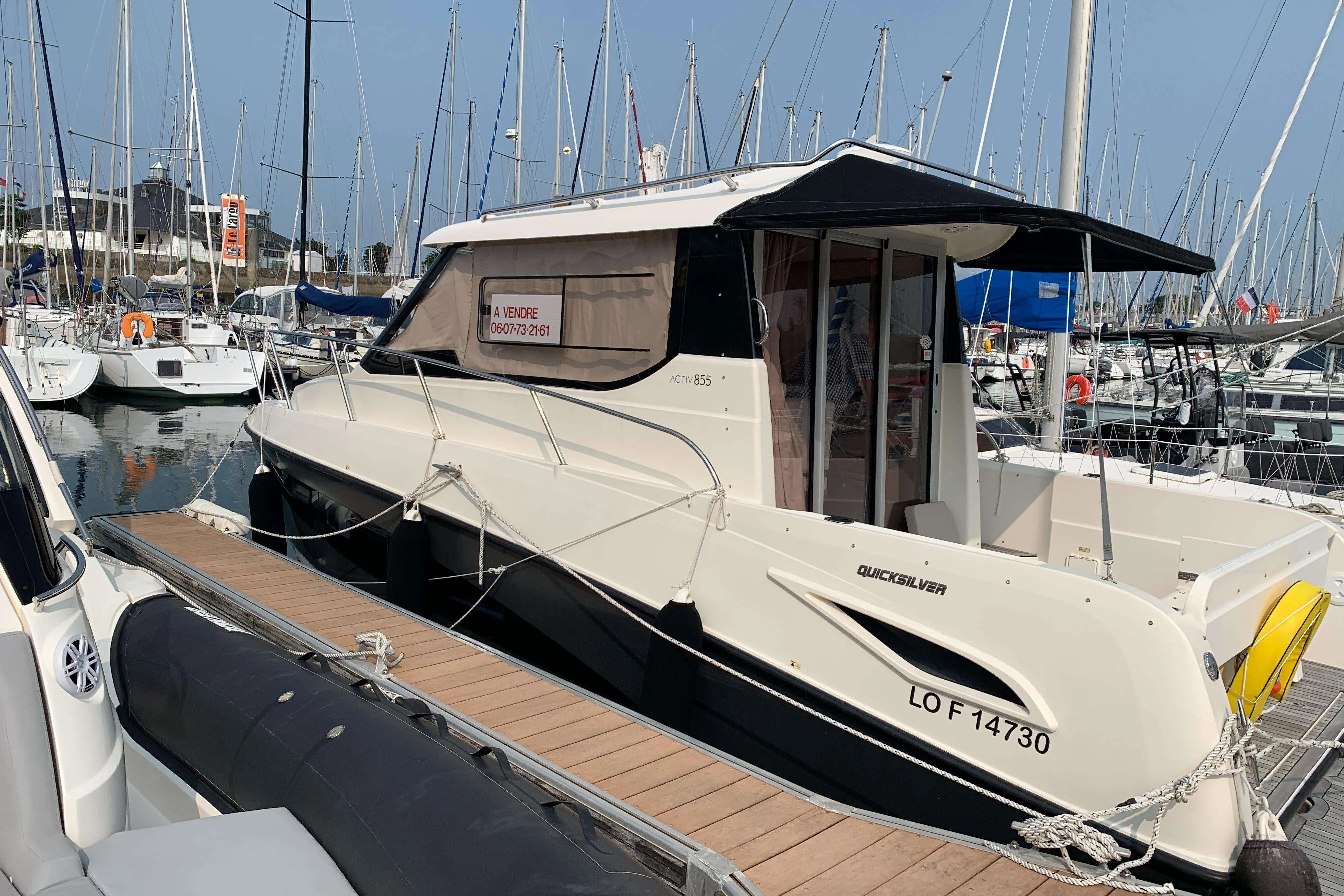 Quicksilver Activ 855 Weekend — Bateau à moteur blanc amarré dans une marina, vu de trois quarts.