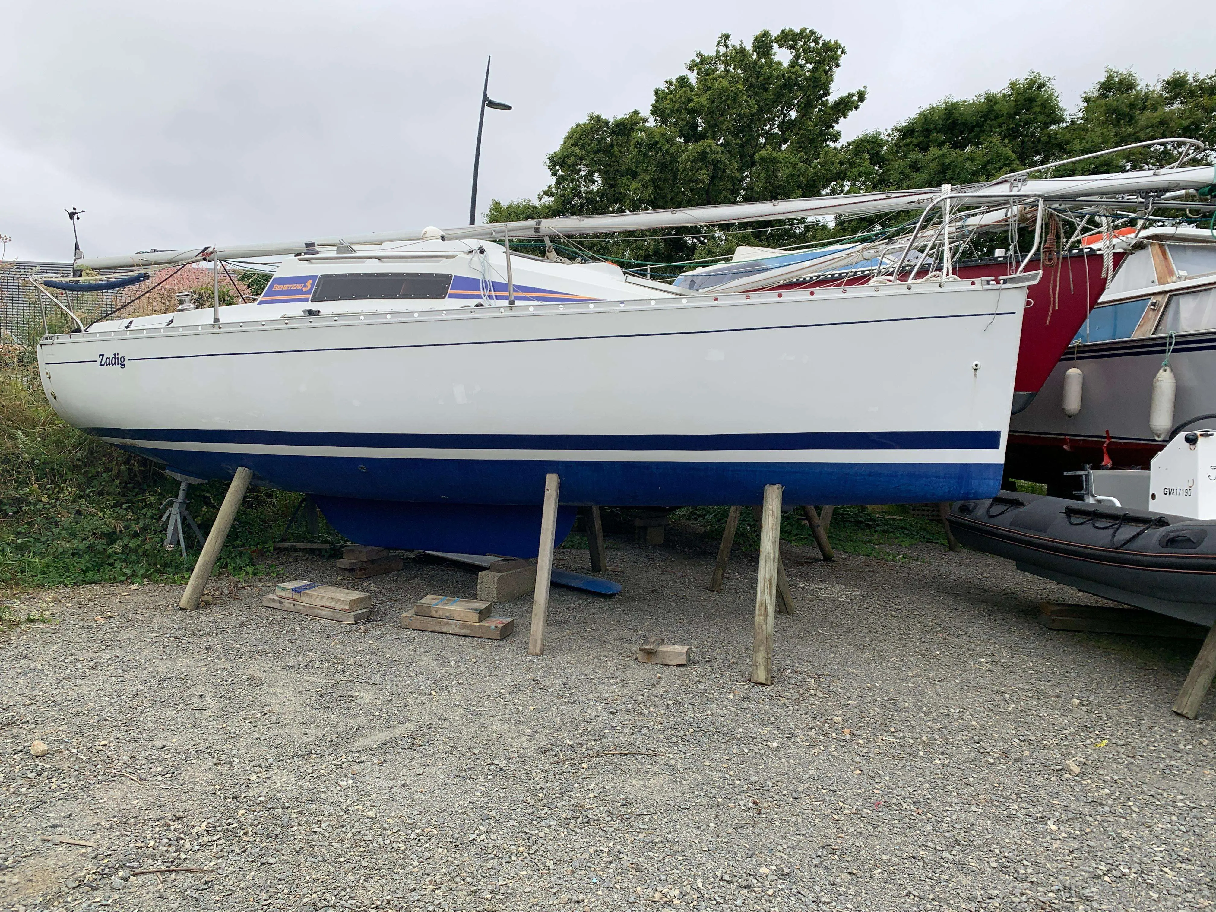 Beneteau First 235 — Voilier blanc et bleu vu de profil, posé sur bers dans un chantier naval.