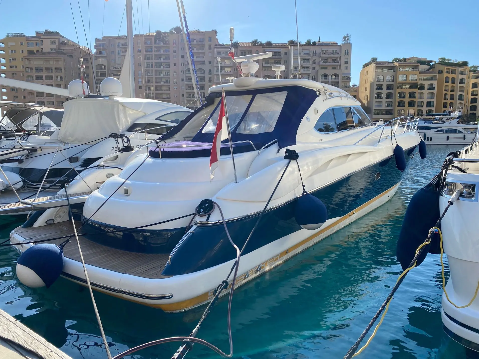 Sunseeker Predator 58 — Bateau à moteur blanc et bleu amarré dans un port, vu de trois quarts arrière.