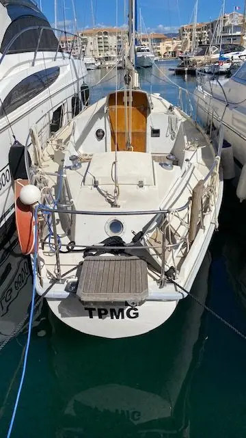 Amel Kirk — Voilier blanc amarré dans un port, photographié depuis l’arrière.