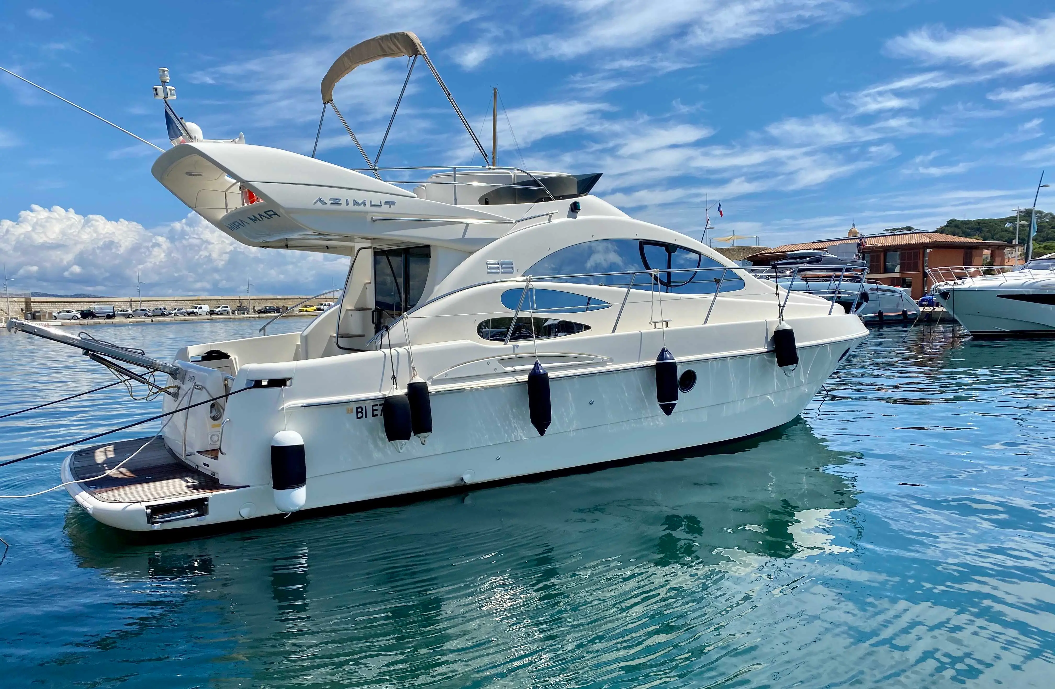 Azimut 39 — Bateau à moteur blanc vu de trois quarts arrière dans une marina ensoleillée.