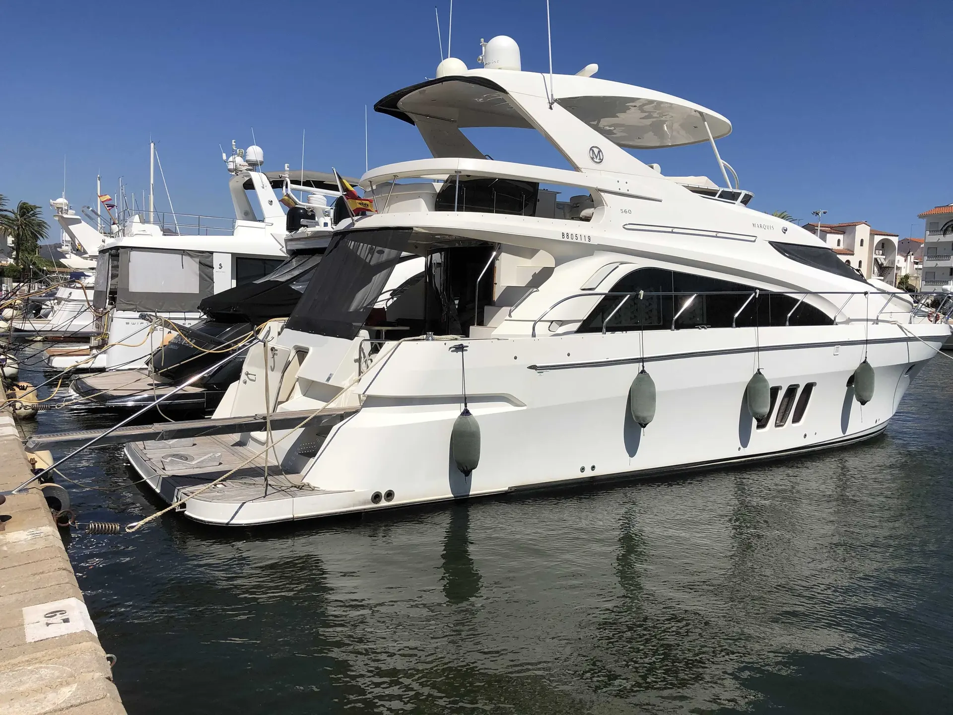 Marquis Yachts 560 — Yacht blanc amarré dans une marina, photographié de trois quarts par l'arrière.