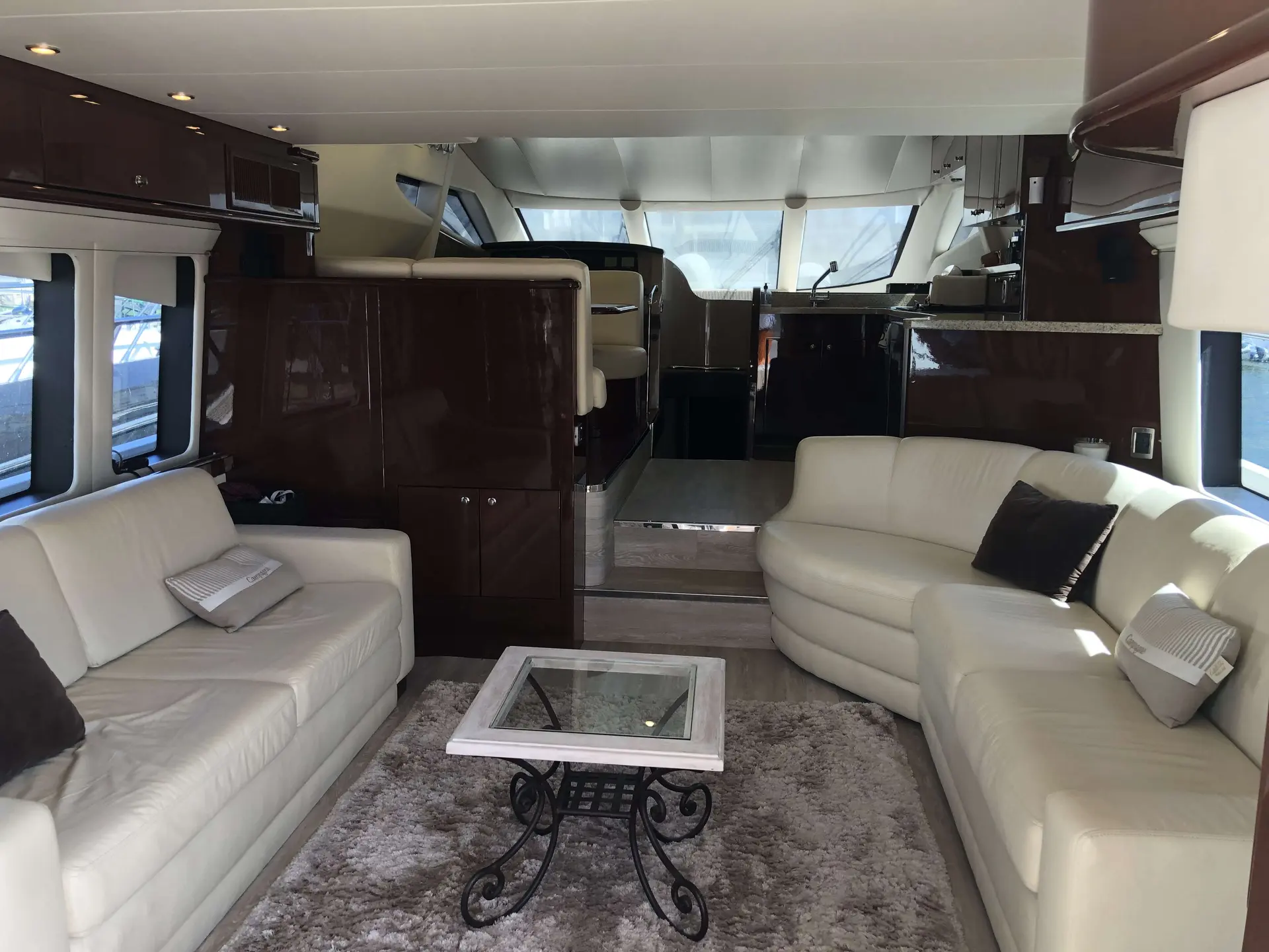 Marquis Yachts 560 — Salon intérieur avec canapés, table basse et poste de pilotage à l’avant.