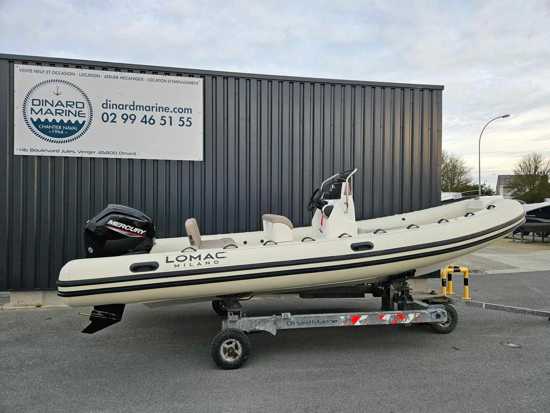 Lomac 600 Turismo — Bateau pneumatique blanc présenté sur une remorque devant un bâtiment nautique.