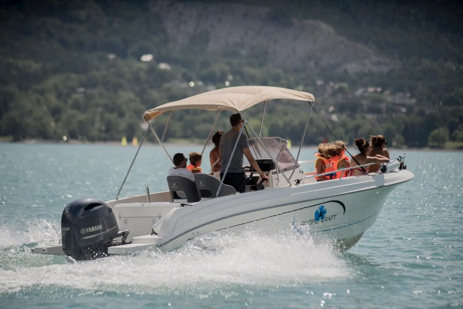 Pacific Craft 670 Plaisance 200cv — Bateau à moteur naviguant sur un lac, avec plusieurs passagers à bord.