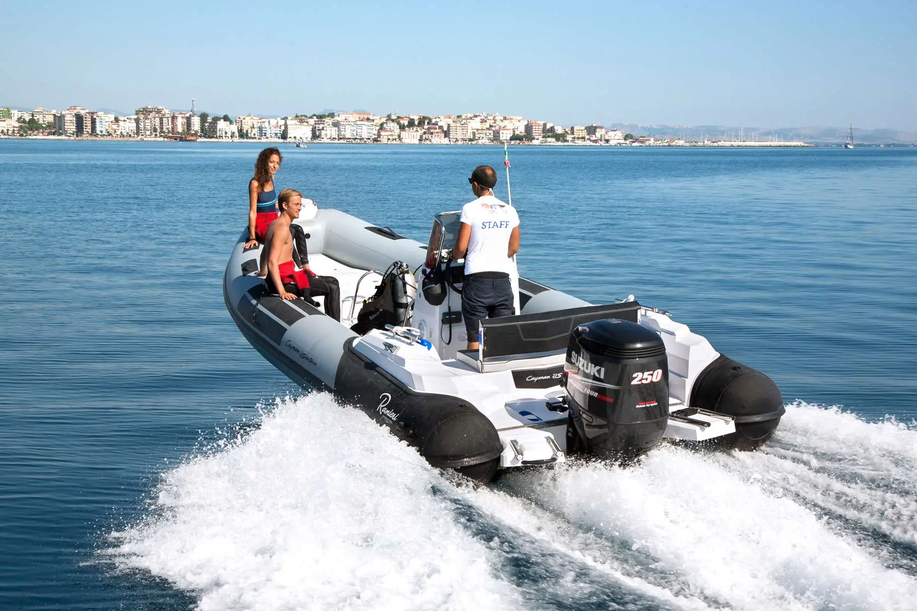 Ranieri Cayman 26 Sport Diving — Bateau pneumatique naviguant à grande vitesse devant une ville côtière.