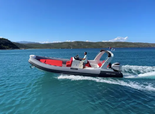 Marsea CM 180 — Bateau semi-rigide gris et rouge naviguant sur une mer turquoise.