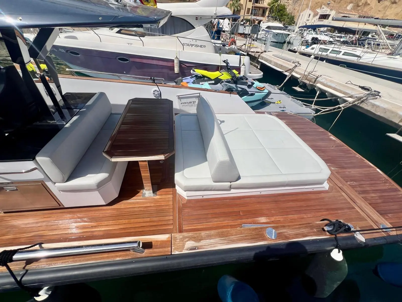Focus Yachts Forza 37 — Vue du cockpit arrière avec banquettes, table et bain de soleil sur le pont.