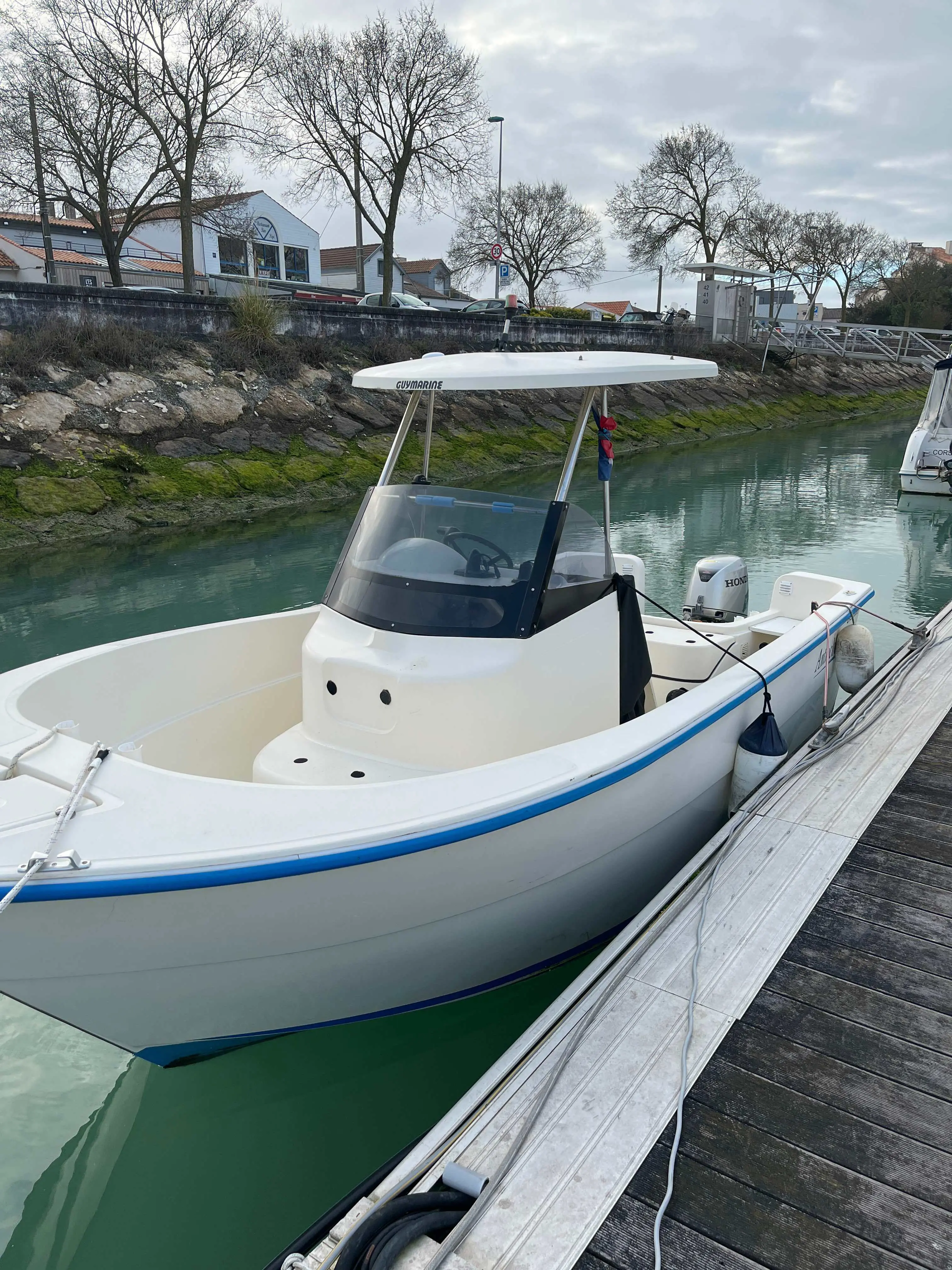 Guymarine Antioche — Bateau à moteur blanc amarré à un ponton, vu de trois quarts avant.