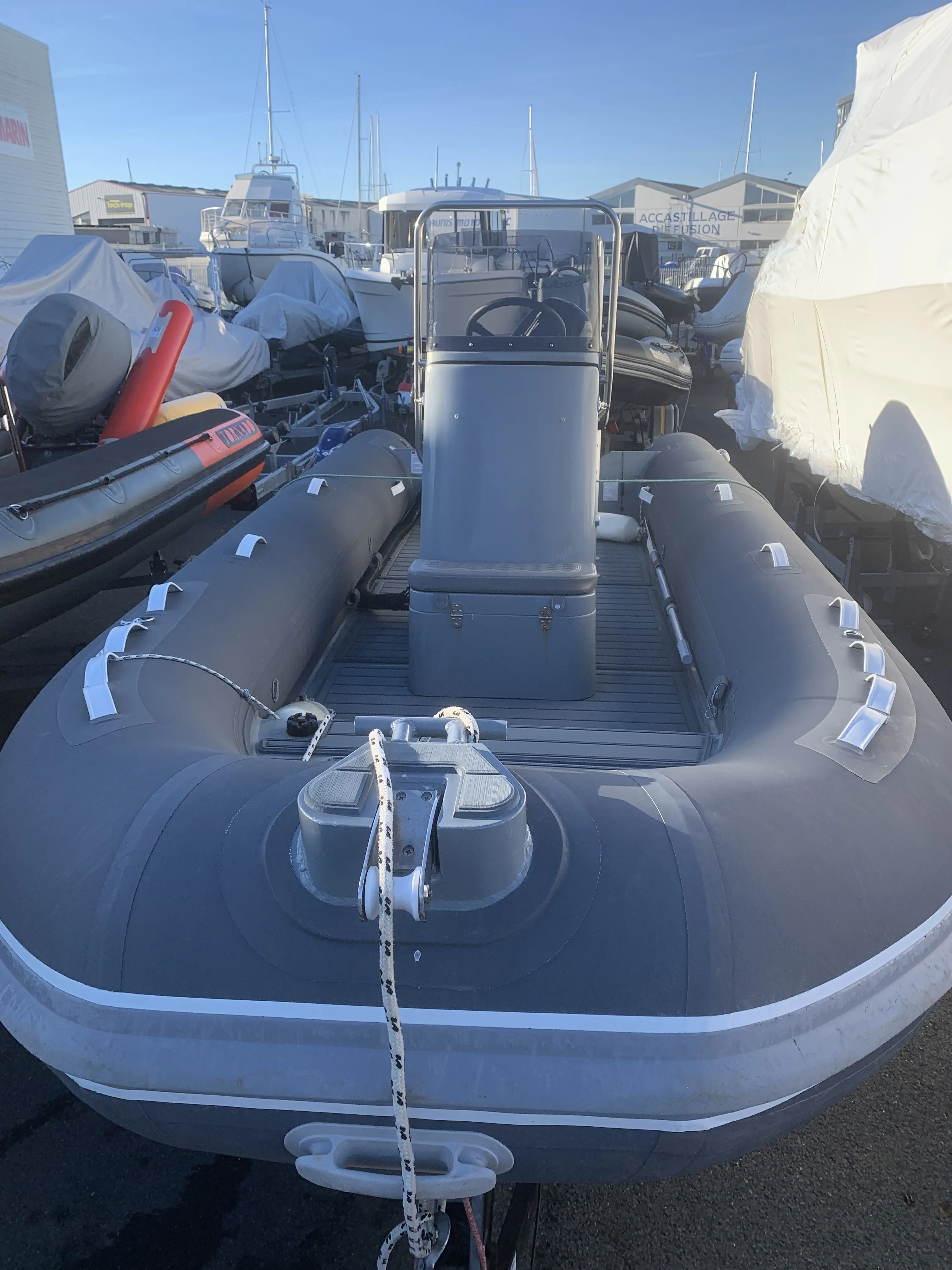 3D Tender Stealth RIB 500 — Vue d’un semi-rigide gris à console centrale, stationné dans un chantier nautique.