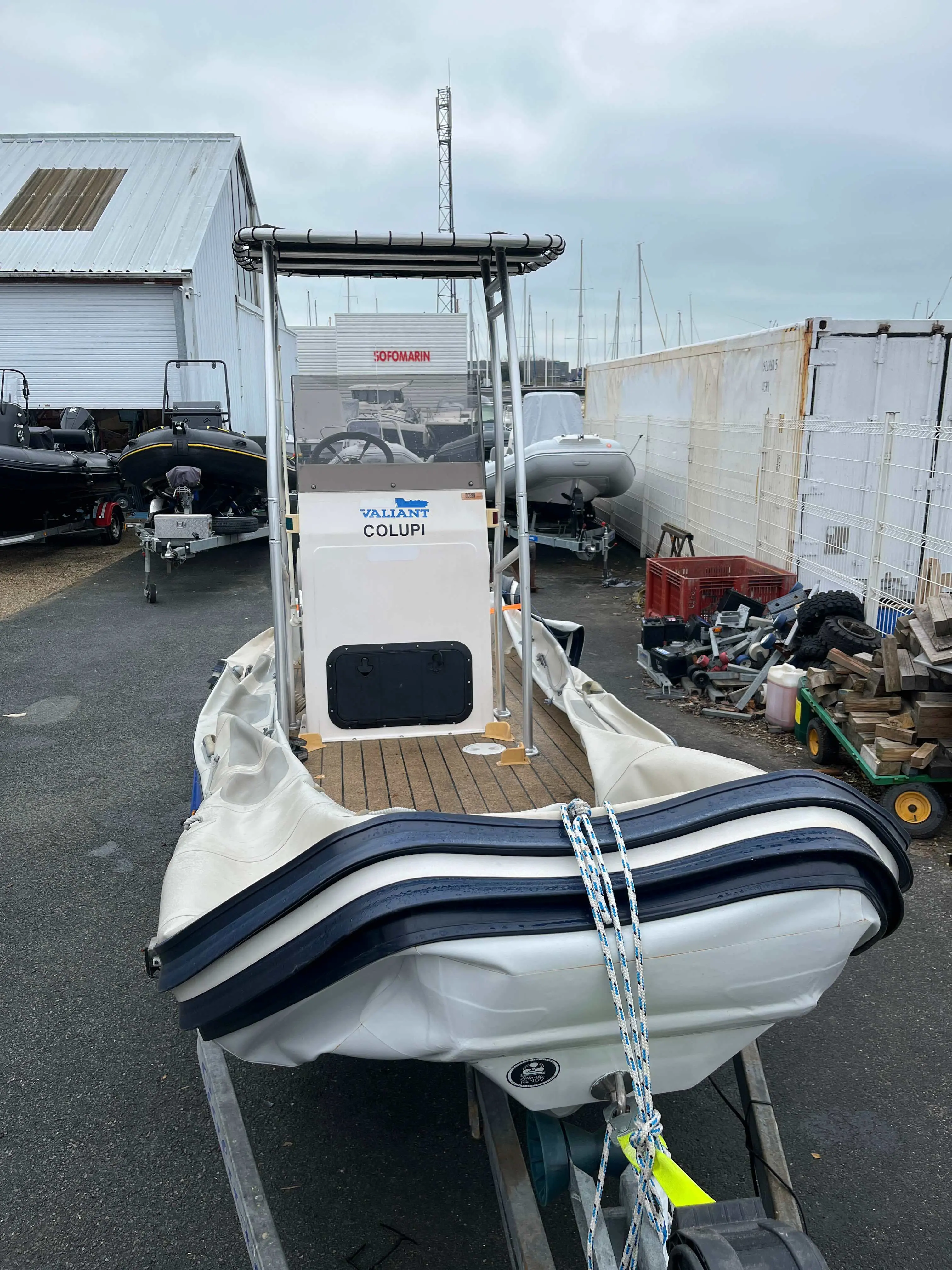 Valiant V 620 Sport — Vue arrière d’un semi-rigide blanc stationné sur sa remorque dans une cour nautique.