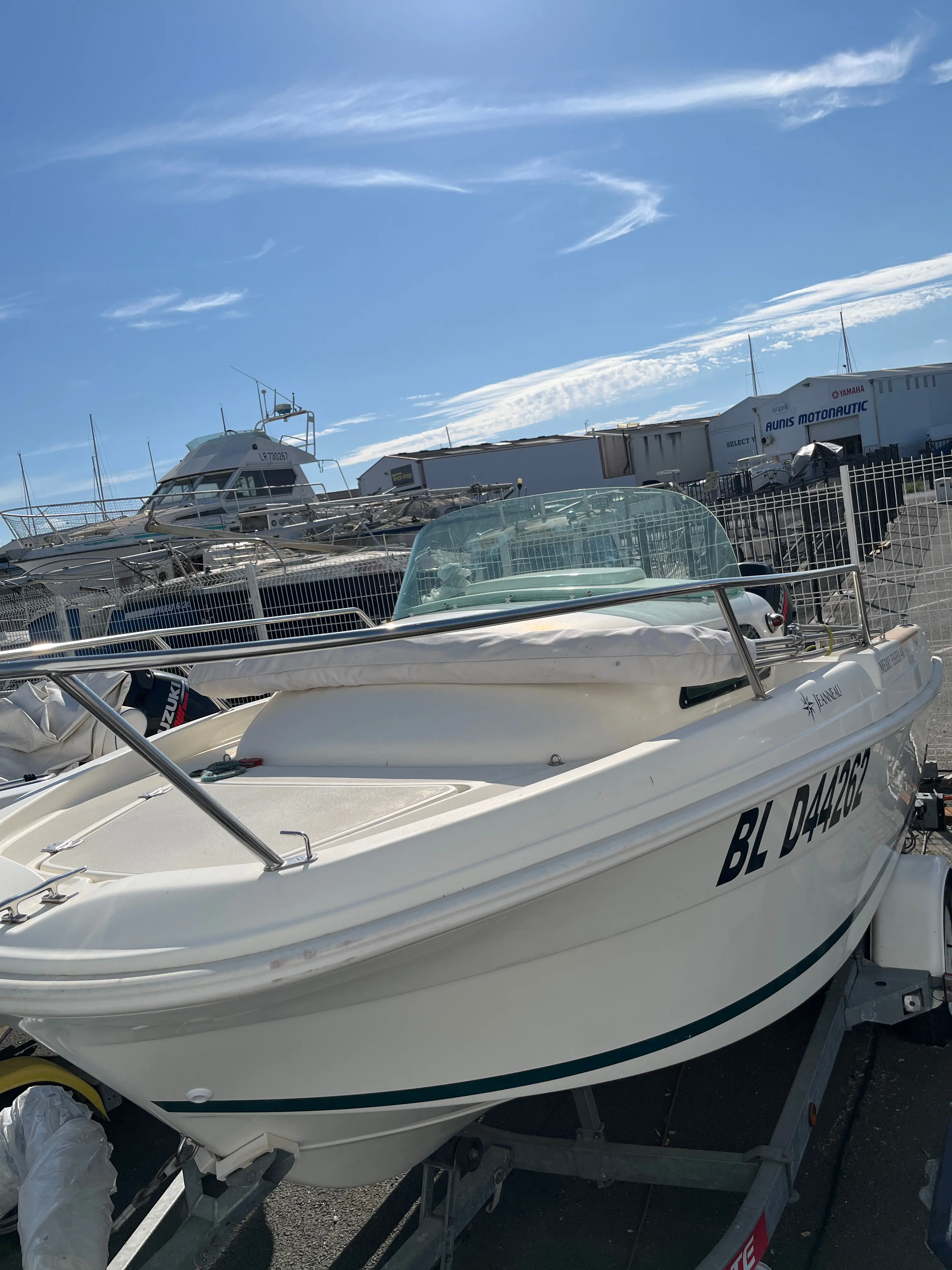 Jeanneau Merry Fisher 480 — Bateau à moteur blanc photographié sur remorque dans un parc nautique.