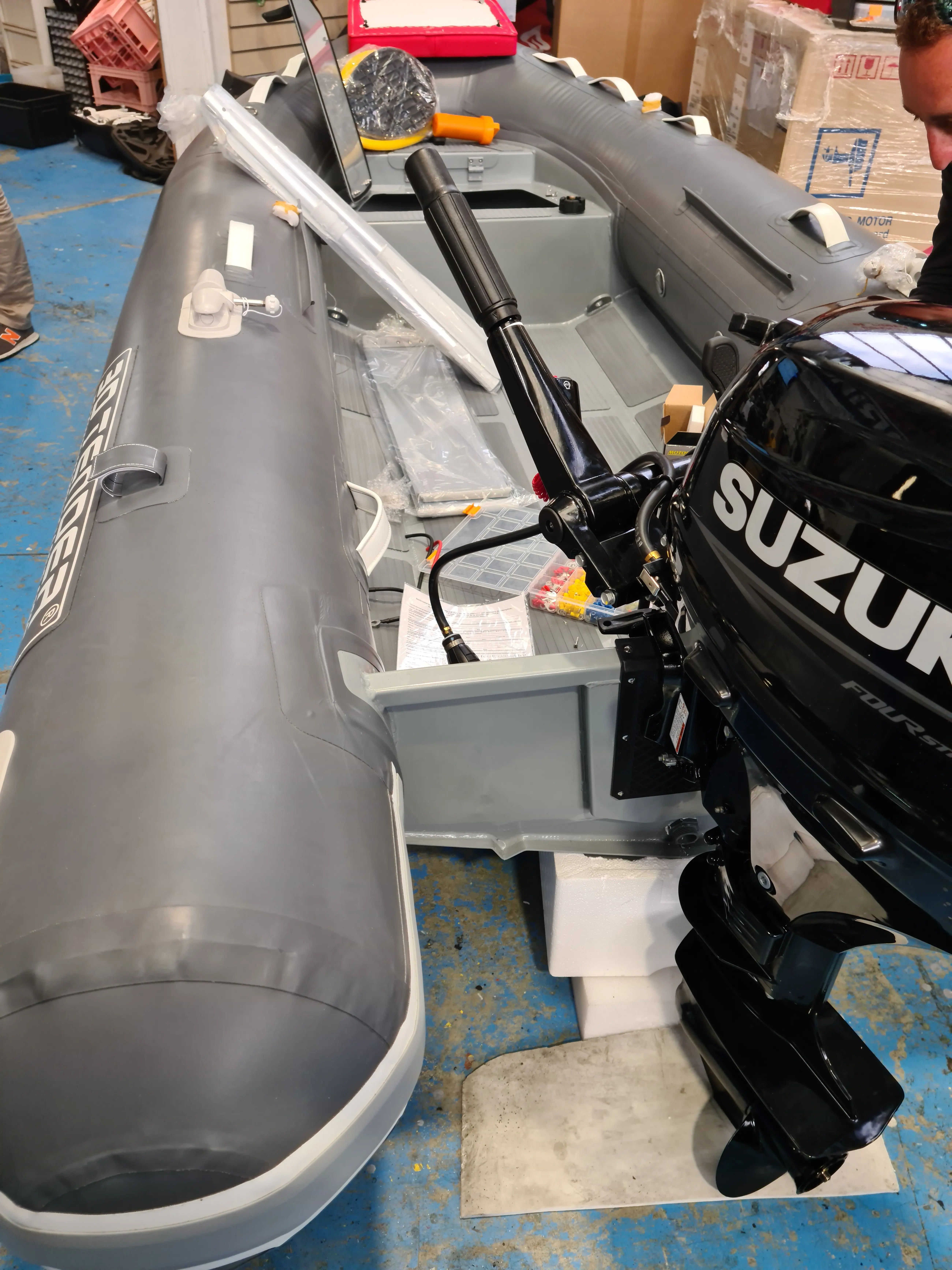 3D Tender Ultimate Rib 340 — Vue intérieure d’un semi-rigide gris équipé d’un moteur hors-bord, en atelier.
