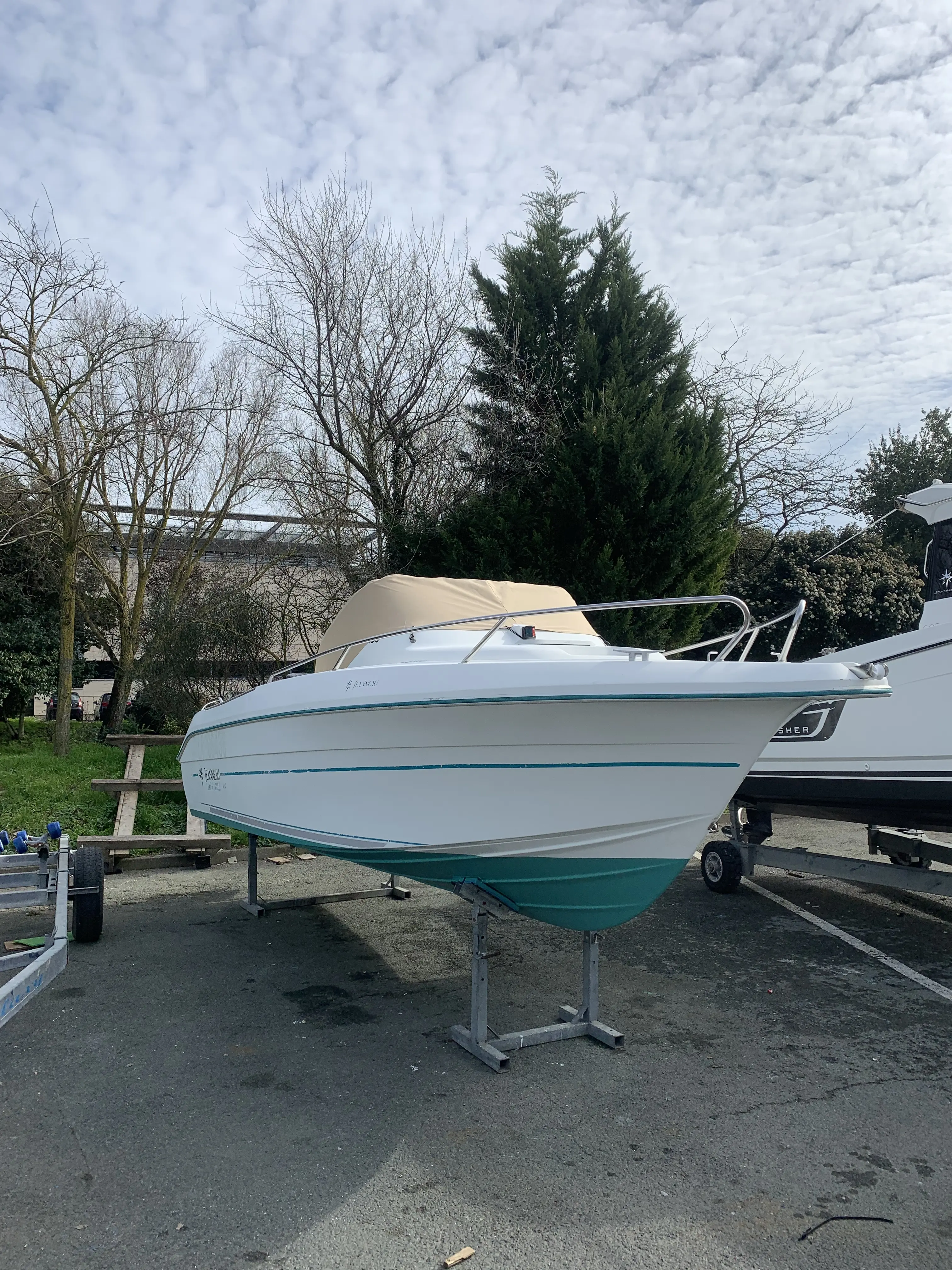 Jeanneau Cap Camarat 615 — Bateau à moteur blanc présenté sur remorque dans un parc de stationnement.