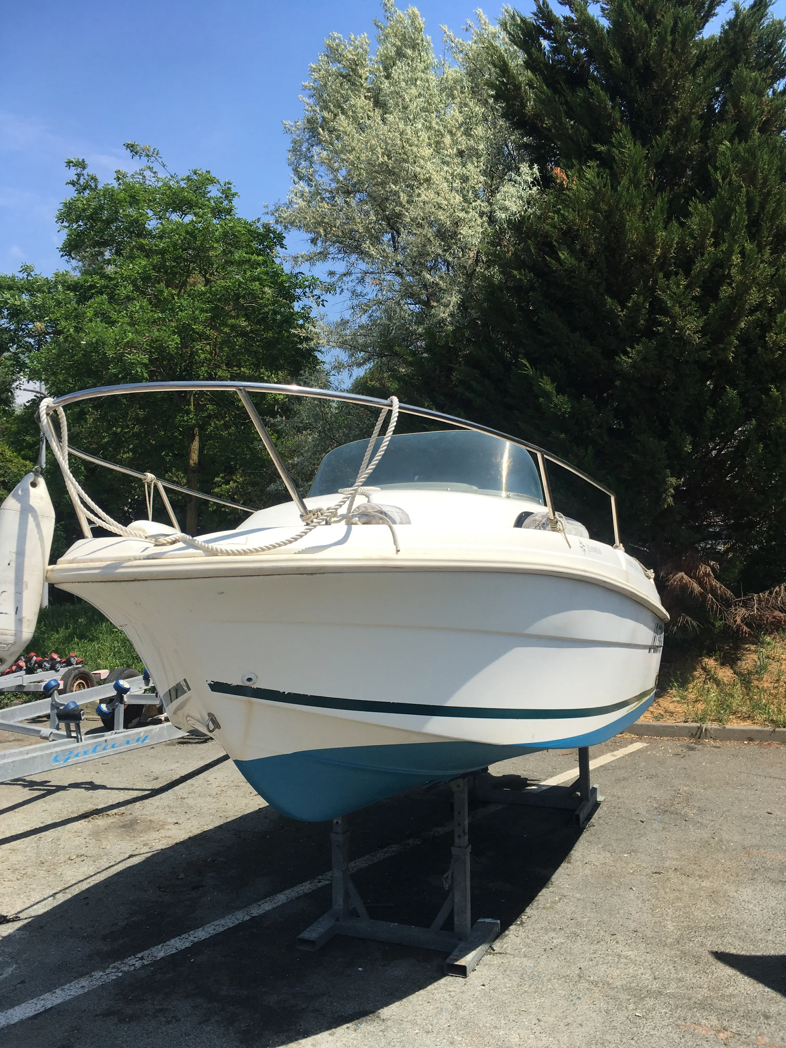 Jeanneau Merry Fisher 480 — Bateau à moteur blanc posé sur sa remorque, photographié de face à terre.