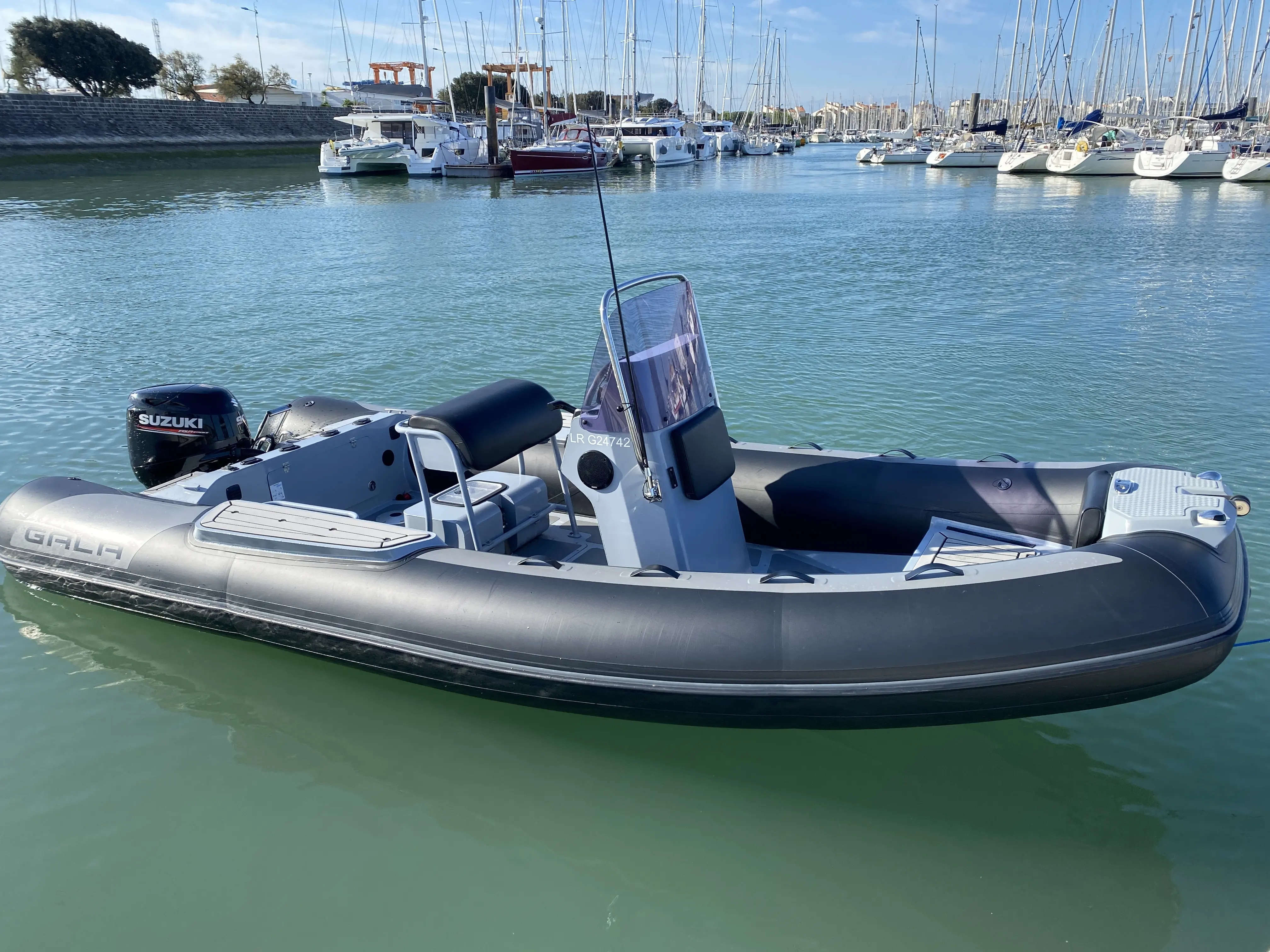 Gala Boats V580 Deluxe — Bateau pneumatique gris à console centrale, photographié dans un port.