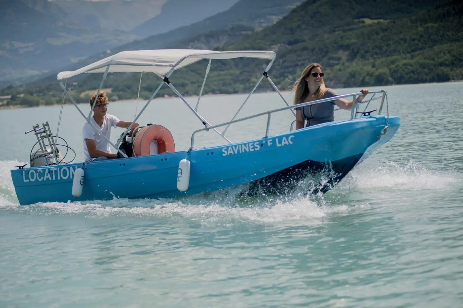 Fun Yak 450 — Bateau bleu à moteur avec taud, naviguant sur un lac montagneux.