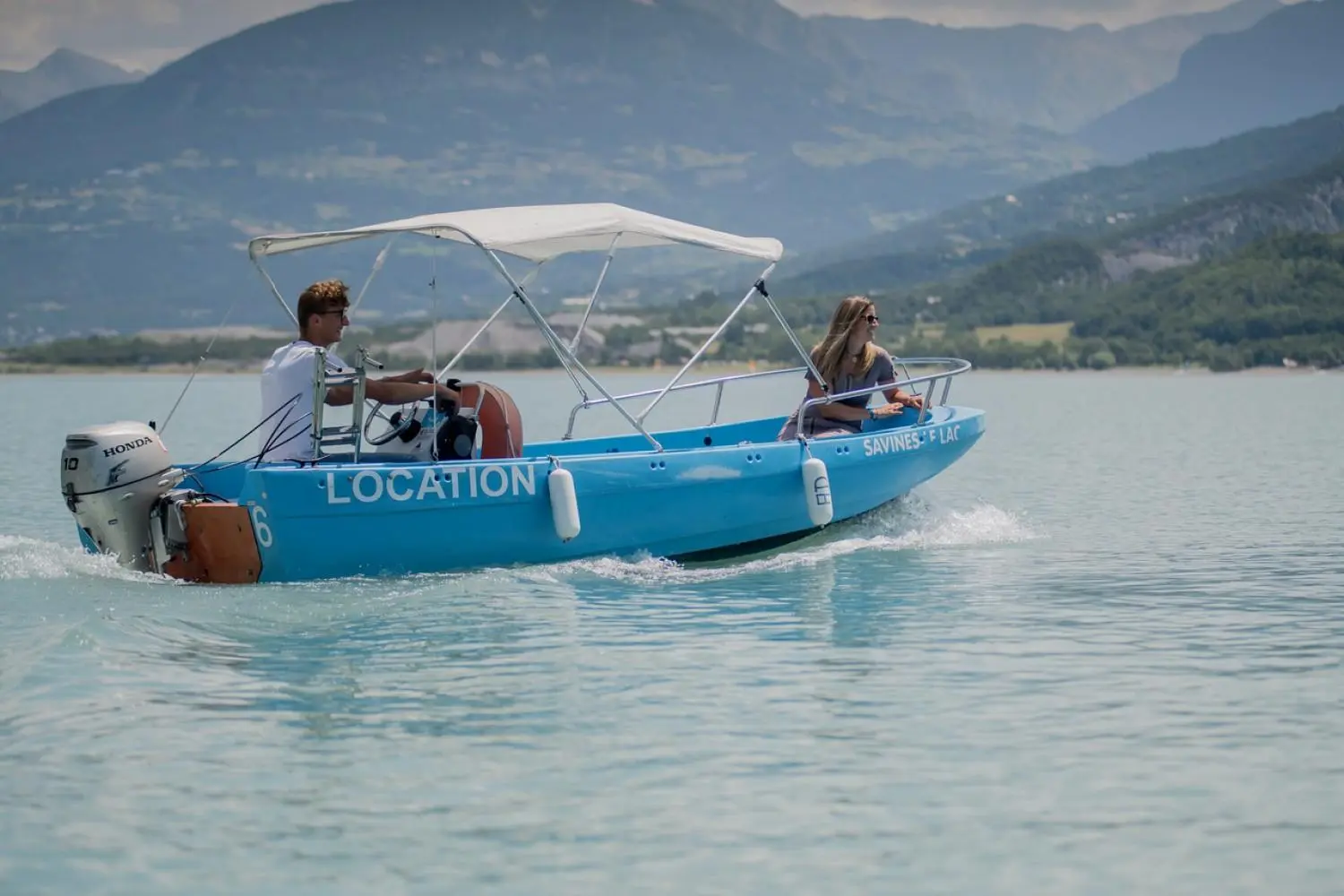 Fun Yak 450 — Bateau à moteur bleu naviguant sur un lac avec deux personnes à bord.