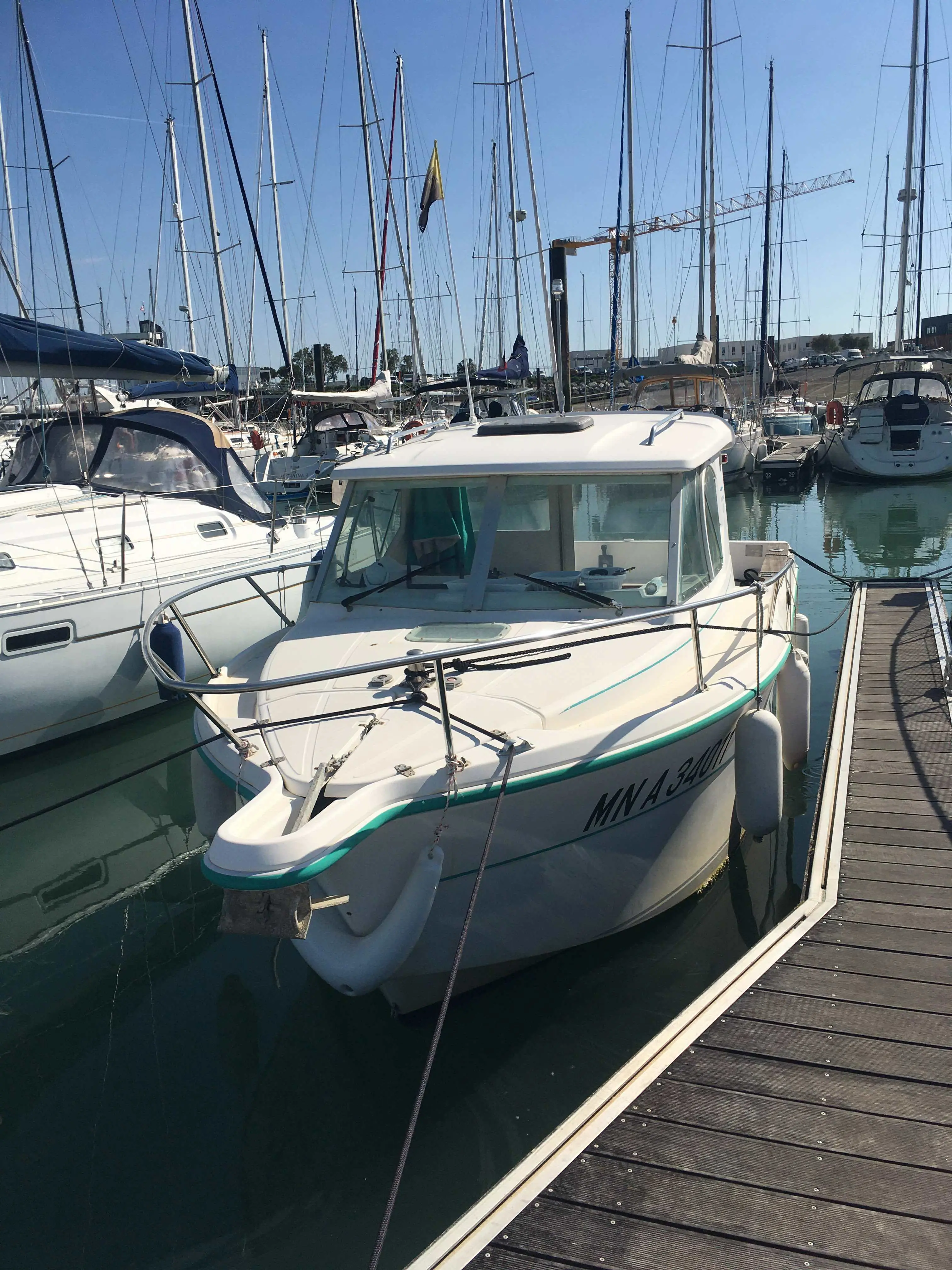Ocqueteau 625 — Bateau à cabine amarré dans un port de plaisance, vu de trois quarts avant.
