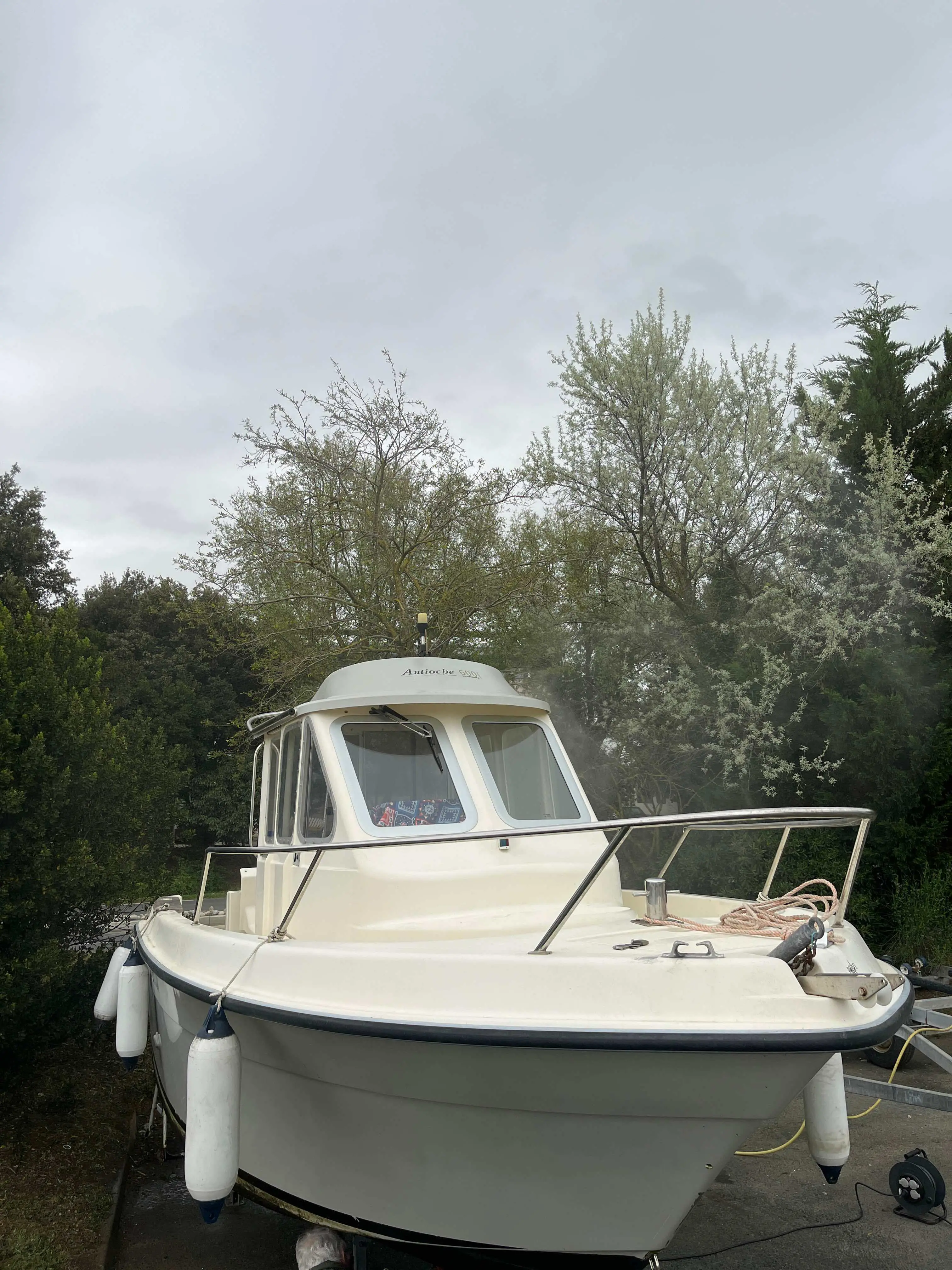 Guymarine Antioche 600 — Bateau à cabine blanche vu de face sur sa remorque, entouré de végétation.