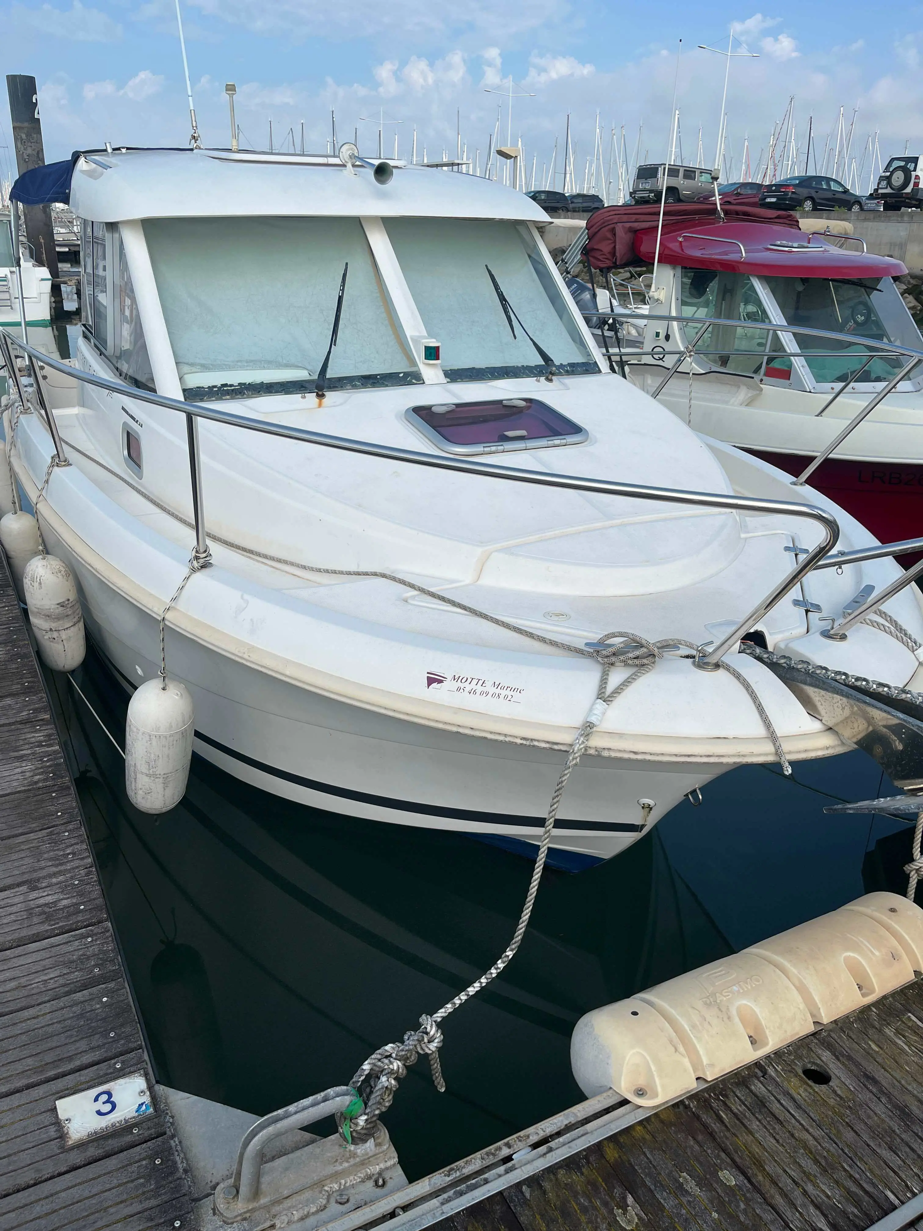 Jeanneau Merry Fisher — Bateau à moteur blanc amarré dans un port, vu de trois quarts avant.