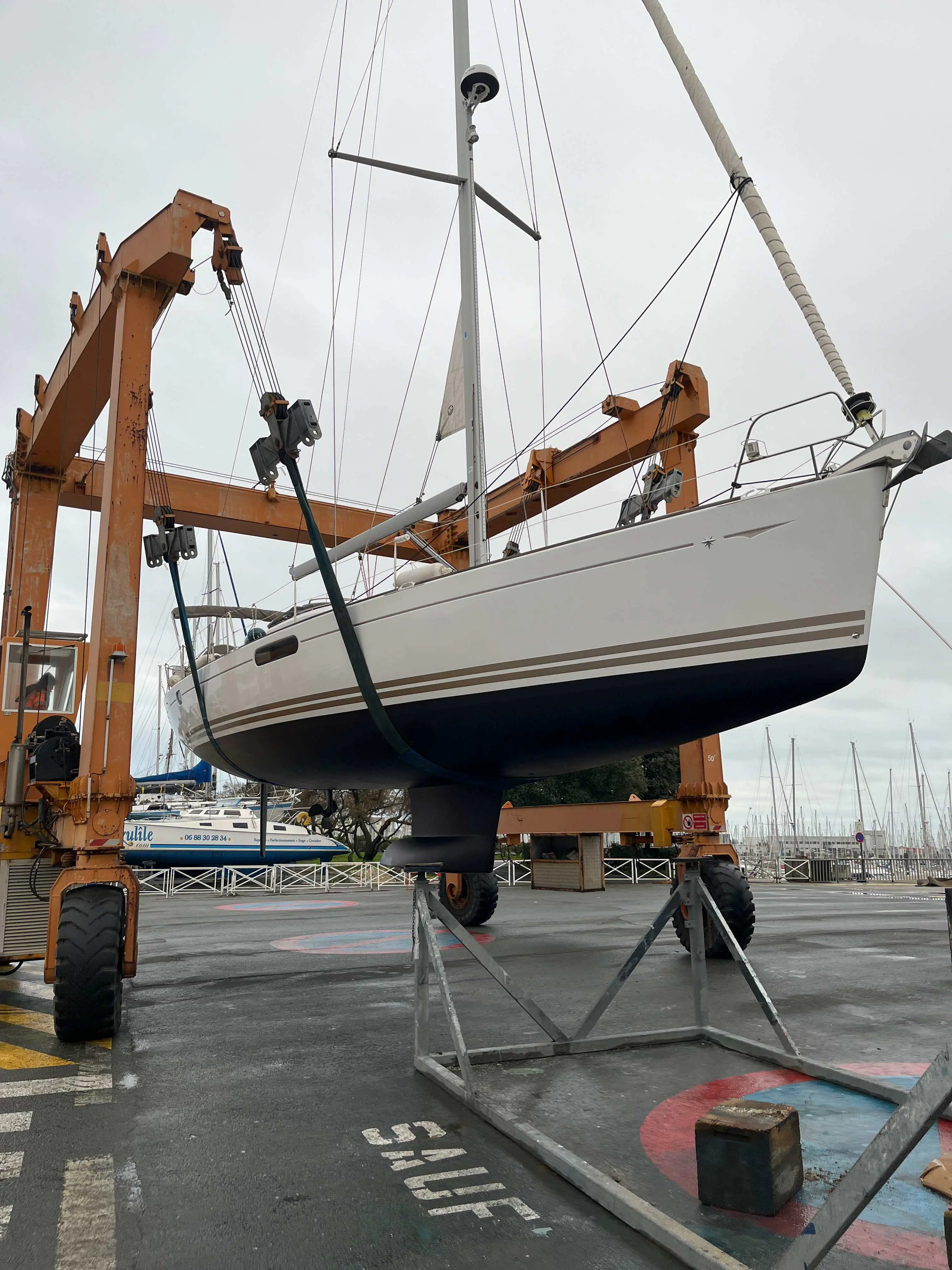 Jeanneau Sun Odyssey 50 DS — Voilier blanc photographié sur un engin de levage dans une marina.