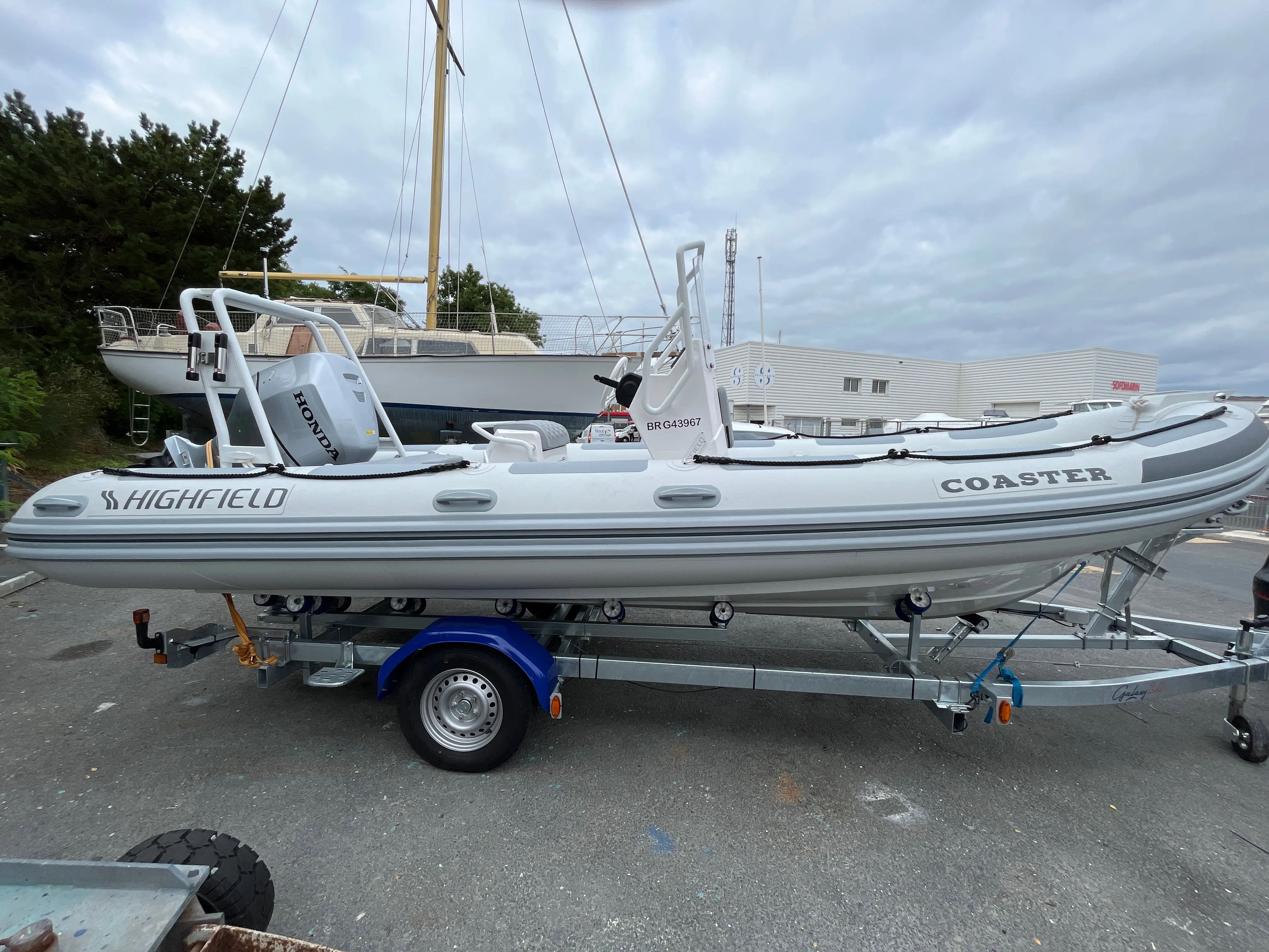 Highfield Coaster 60 — Bateau pneumatique semi-rigide blanc présenté sur une remorque, vu de profil.