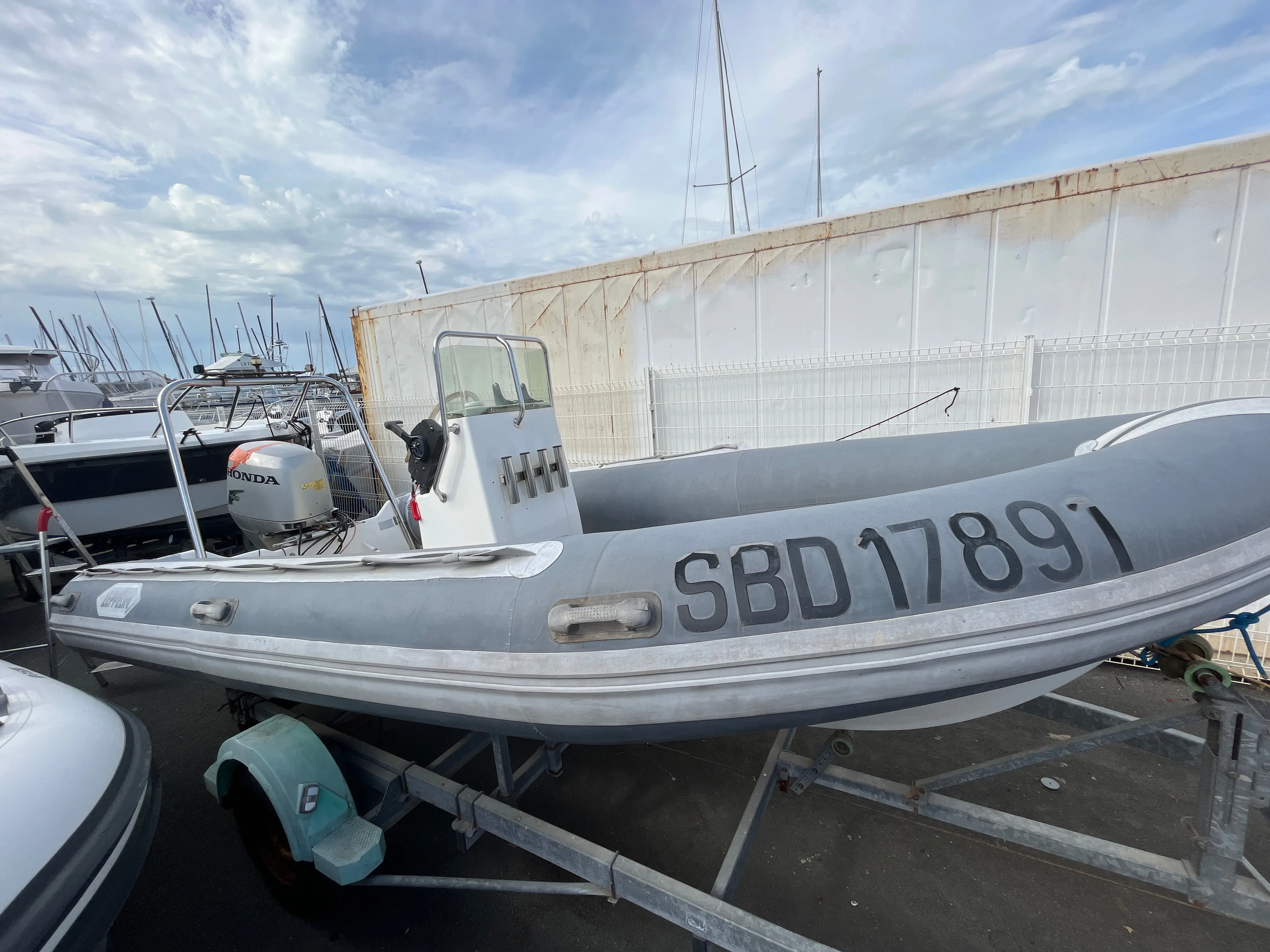 Zeppelin — Semi-rigide gris avec console centrale, moteur hors-bord et remorque au port.