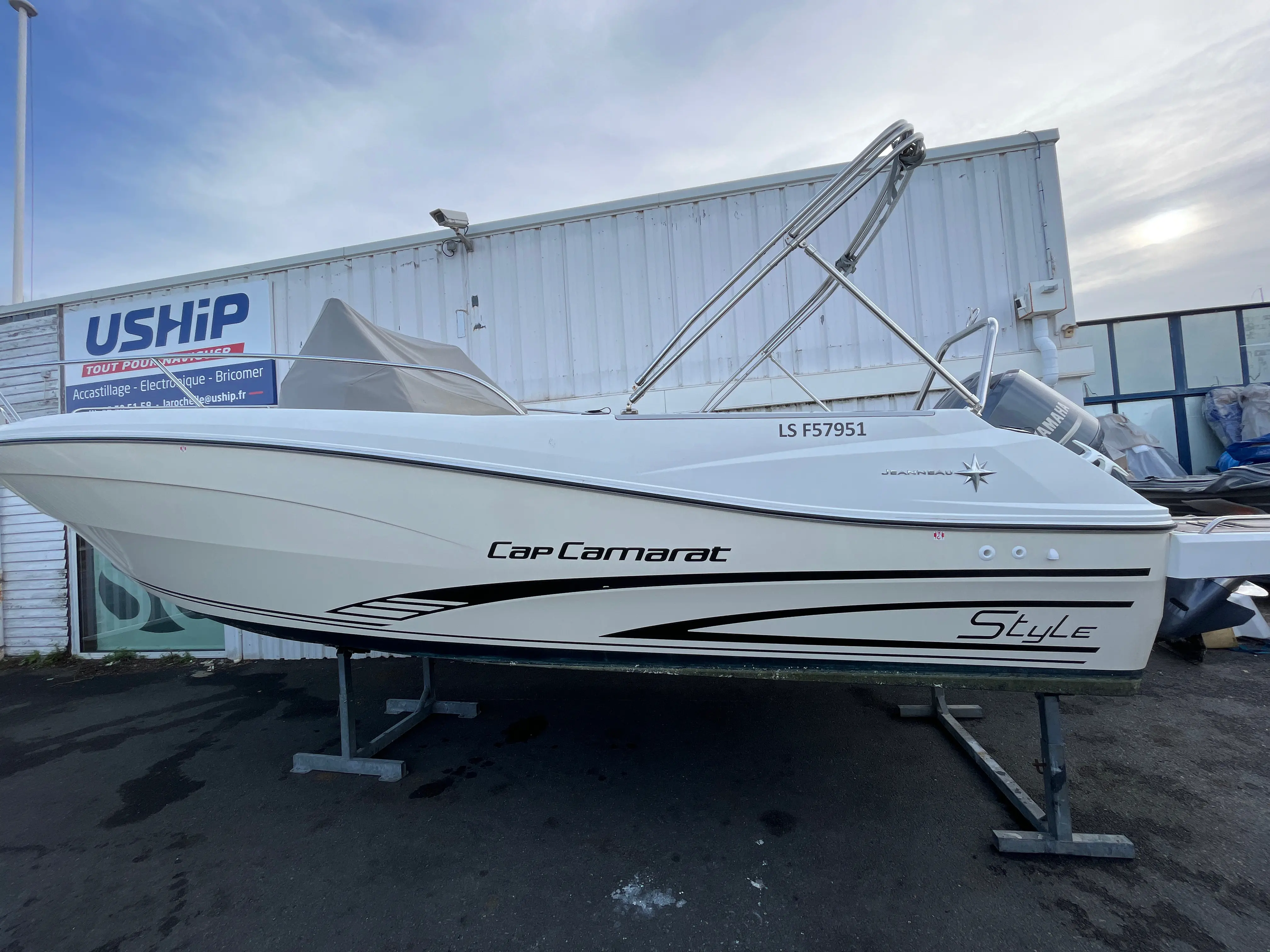 Jeanneau Cap Camarat 7.5 Style — Bateau à moteur Cap Camarat photographié à terre devant un bâtiment nautique.