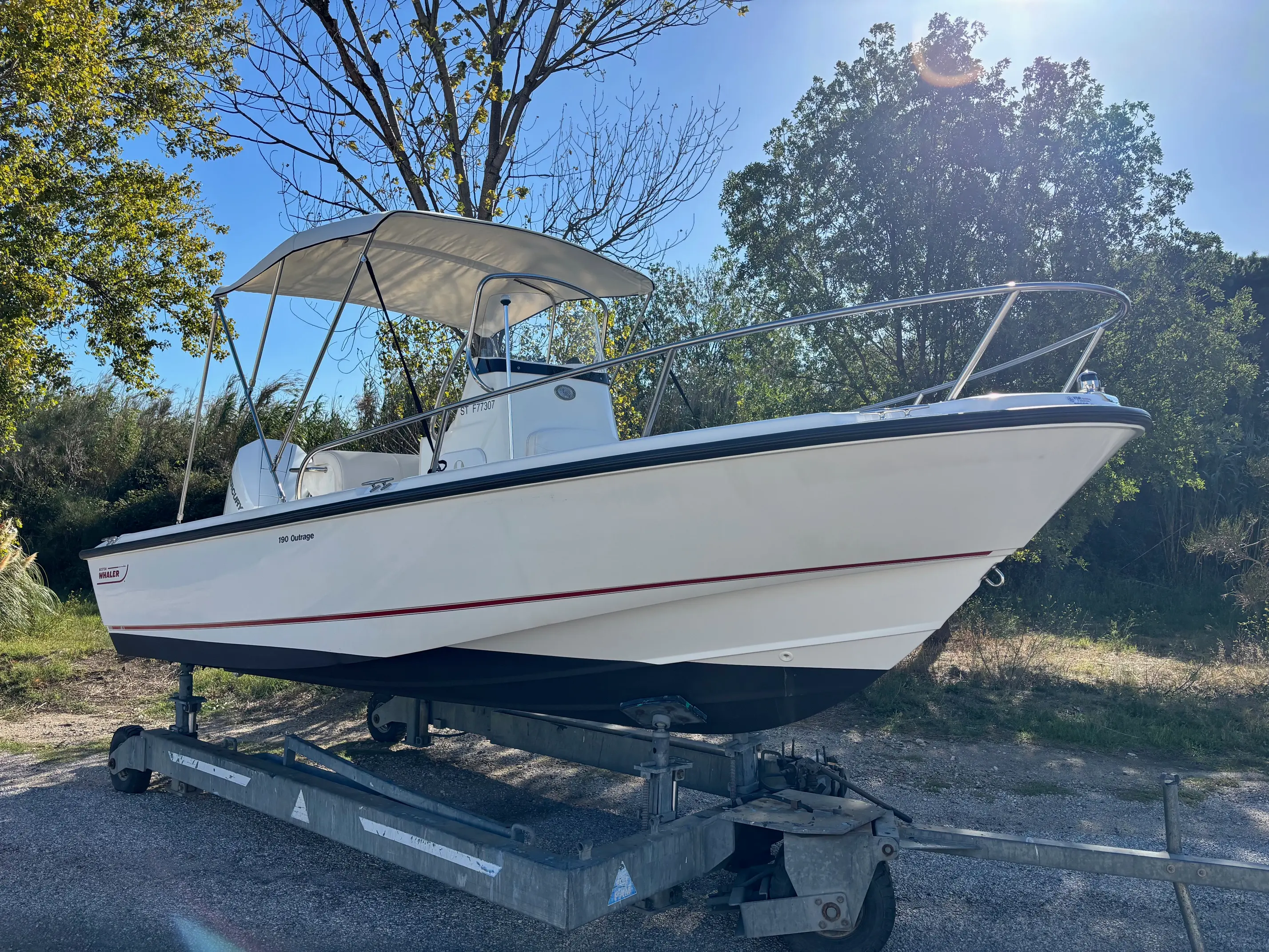 Boston Whaler 190 Outrage — Bateau à moteur blanc sur remorque, photographié de trois quarts à terre.