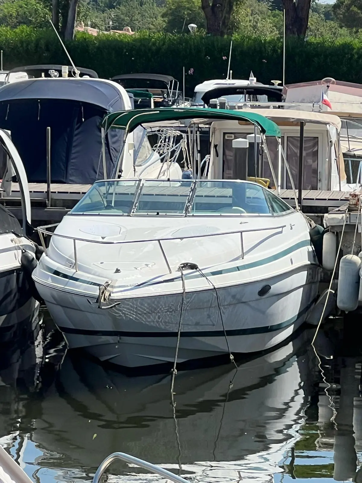 Chris Craft 245 — Bateau à moteur blanc amarré dans un port, vu de face.