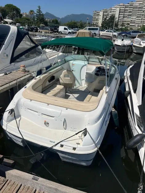 Chris Craft 245 — Bateau à moteur blanc amarré dans une marina, vu en trois quarts arrière.