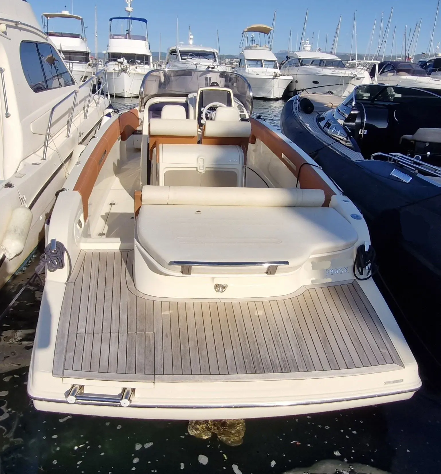 Invictus 280 SX — Vue arrière d’un bateau à console centrale amarré dans une marina.