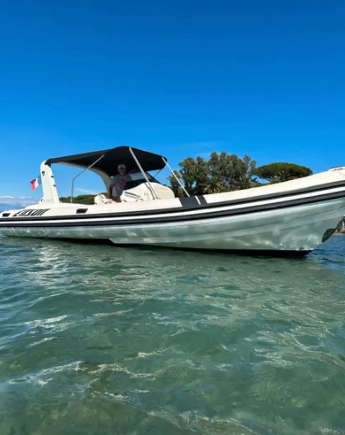 Alson Flash 750 — Bateau semi-rigide vu de profil sur l’eau, avec console centrale et taud noir.