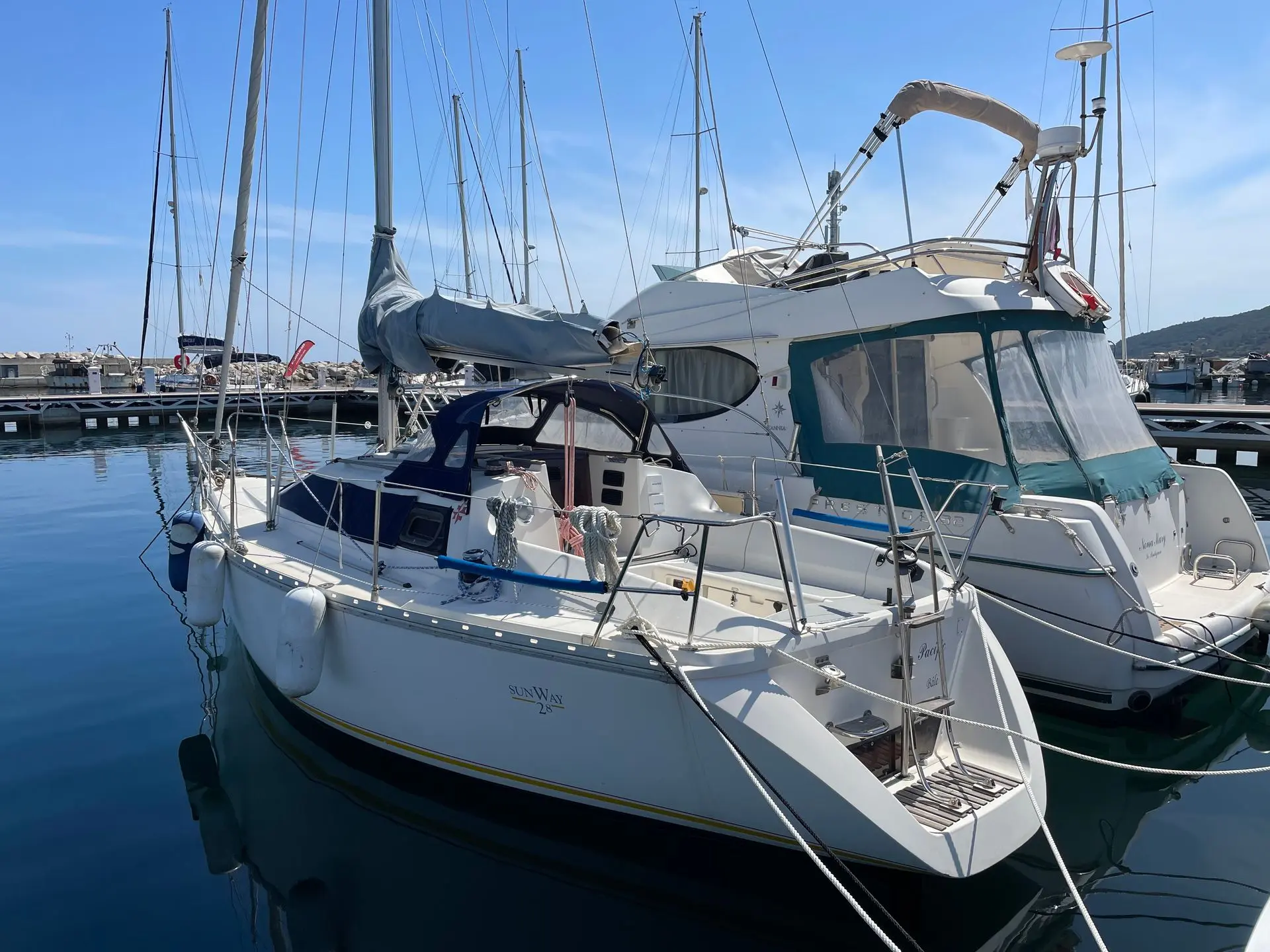 Jeanneau Sun Way 28 — Voilier blanc amarré, vu de trois quarts avant dans un port de plaisance.