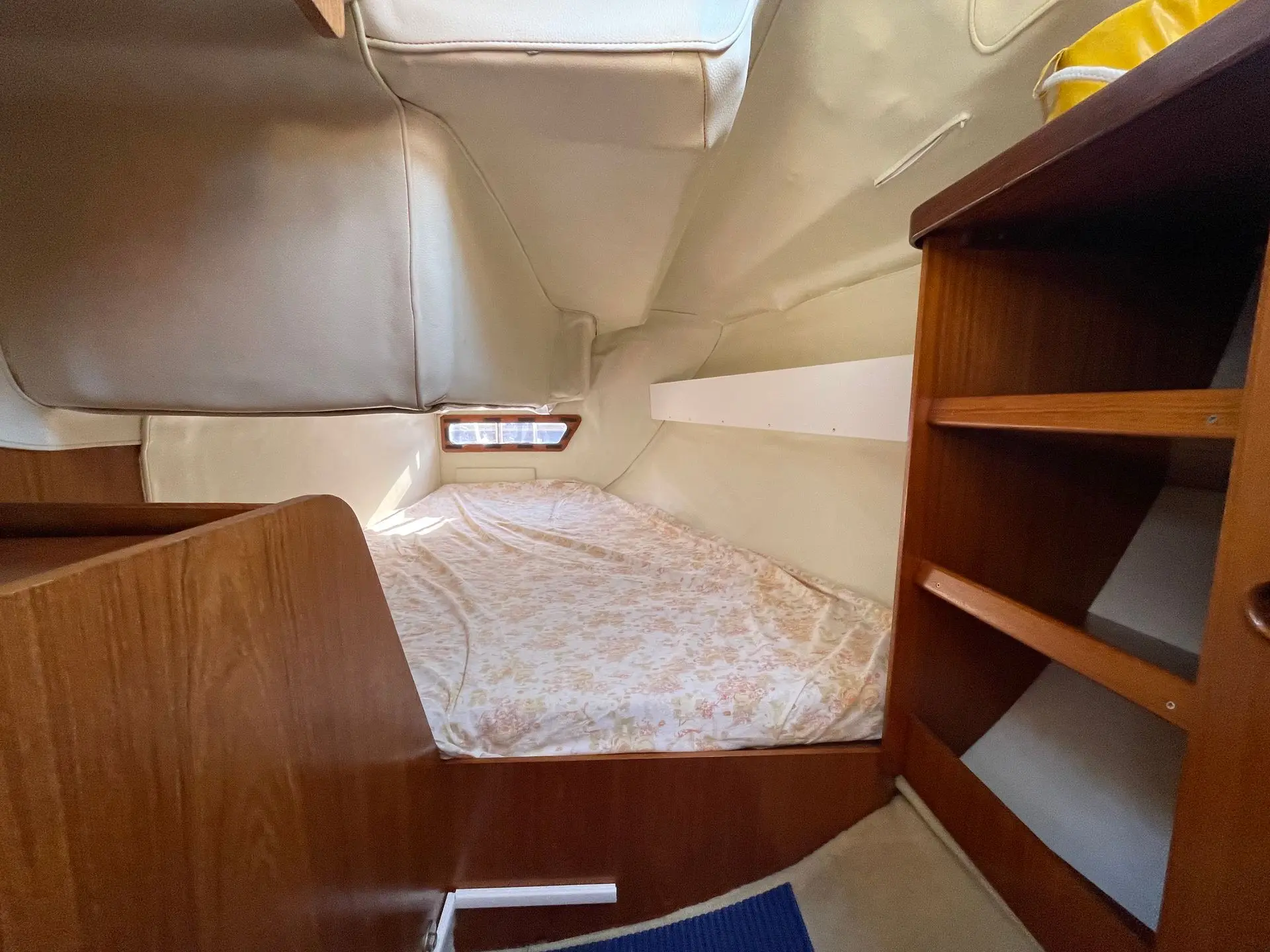 Jeanneau Sun Way 28 — Cabine avant avec couchette double, rangements en bois et hublot.