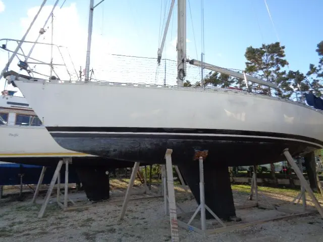 Beneteau First 32 — Voilier blanc photographié à terre sur bers, vu de profil.