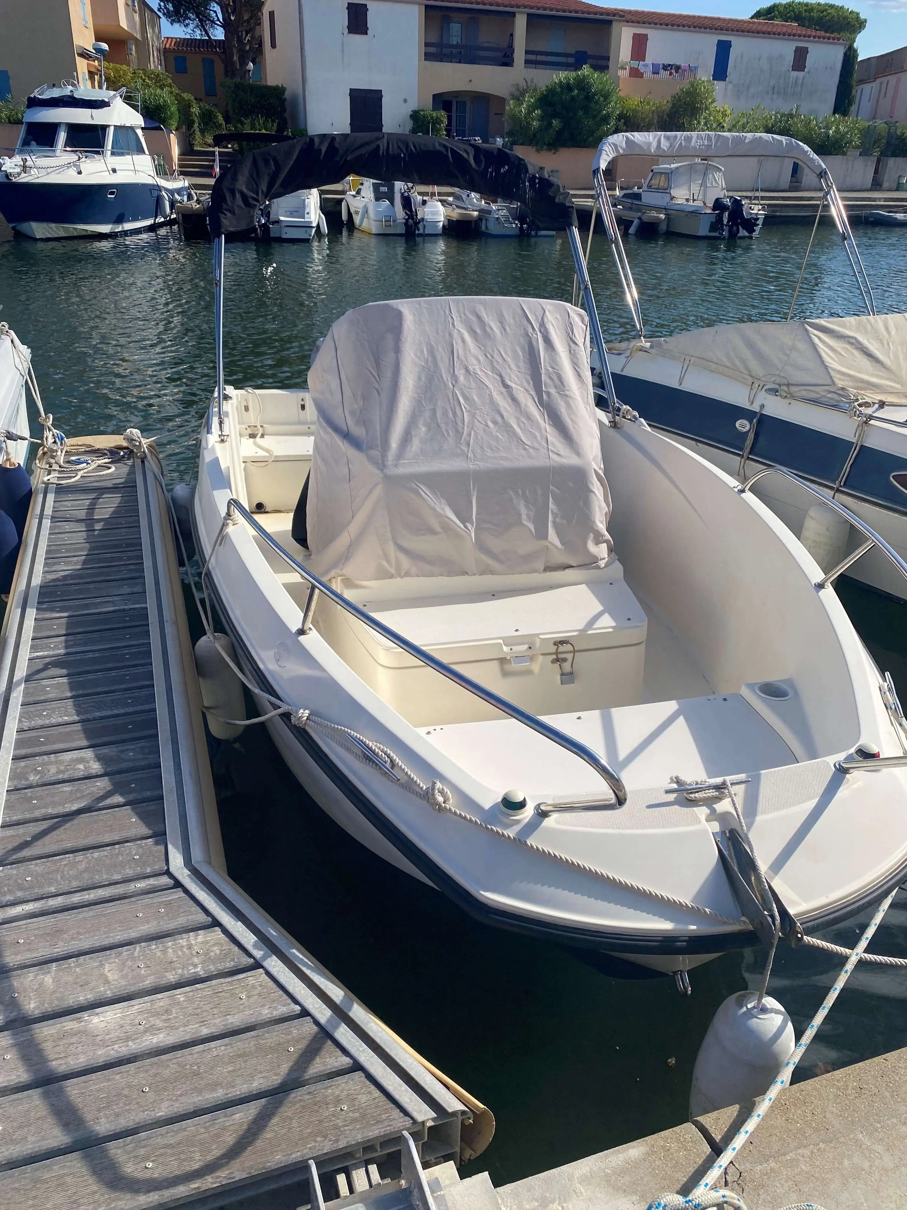 Quicksilver Activ 535 Open — Bateau à moteur amarré au ponton, vu de trois quarts depuis l'avant.
