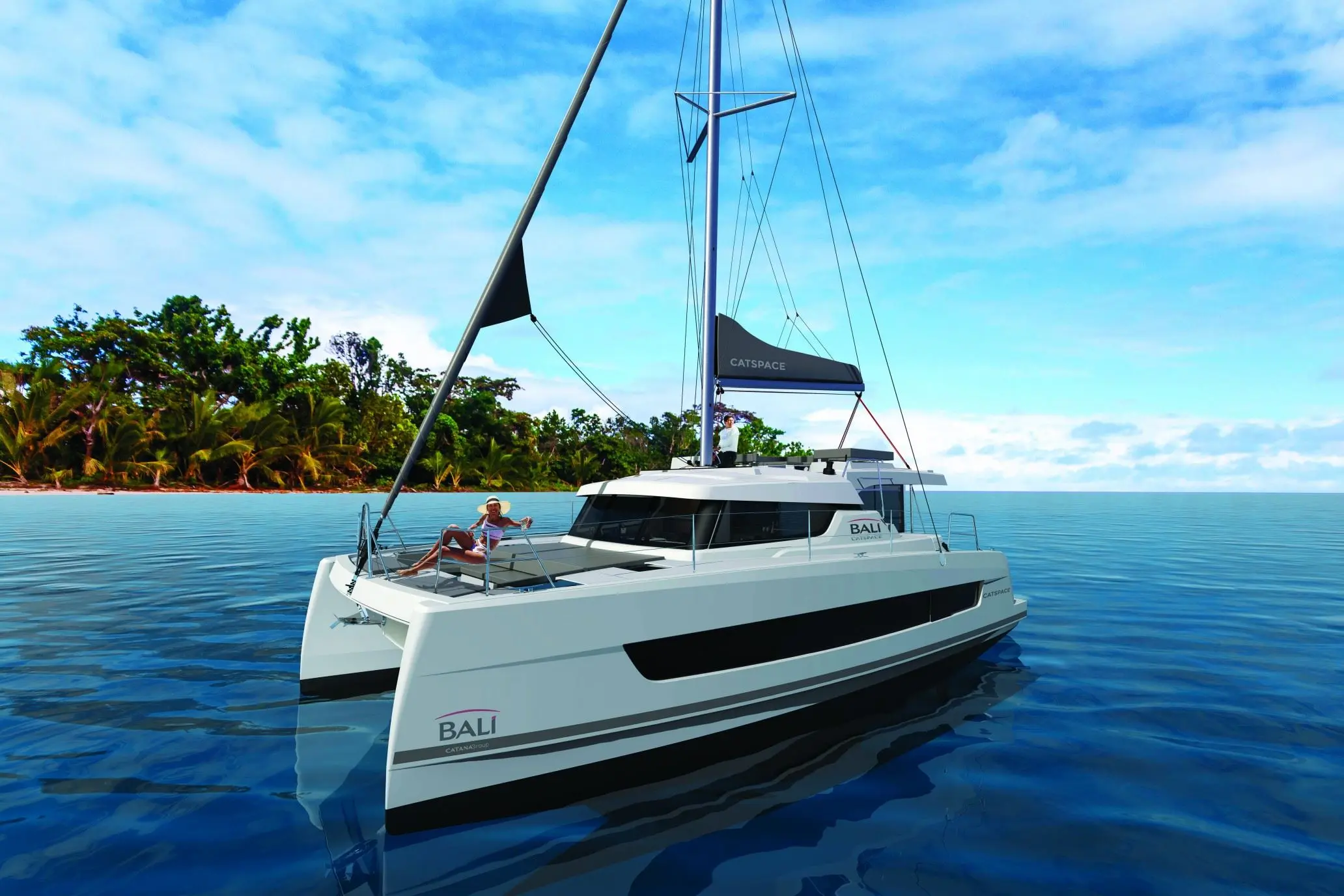 Bali Catamarans Catspace — Catamaran blanc vu de trois quarts dans une baie tropicale, avec une personne à l’avant.