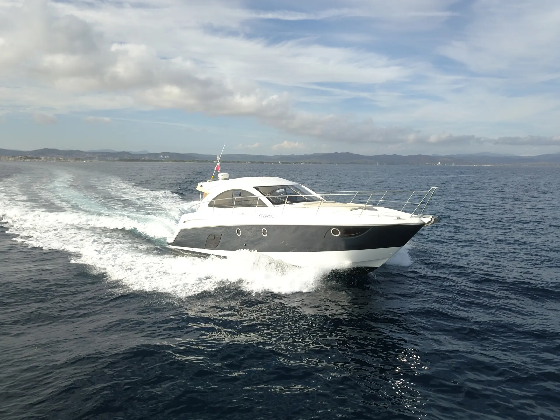 Beneteau Gran Turismo 44 — Bateau à moteur blanc et gris naviguant au large, vu de trois quarts.