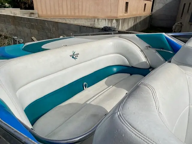 Wellcraft Scarab 29 — Vue rapprochée des sièges rembourrés blancs et turquoise du cockpit d’un bateau.