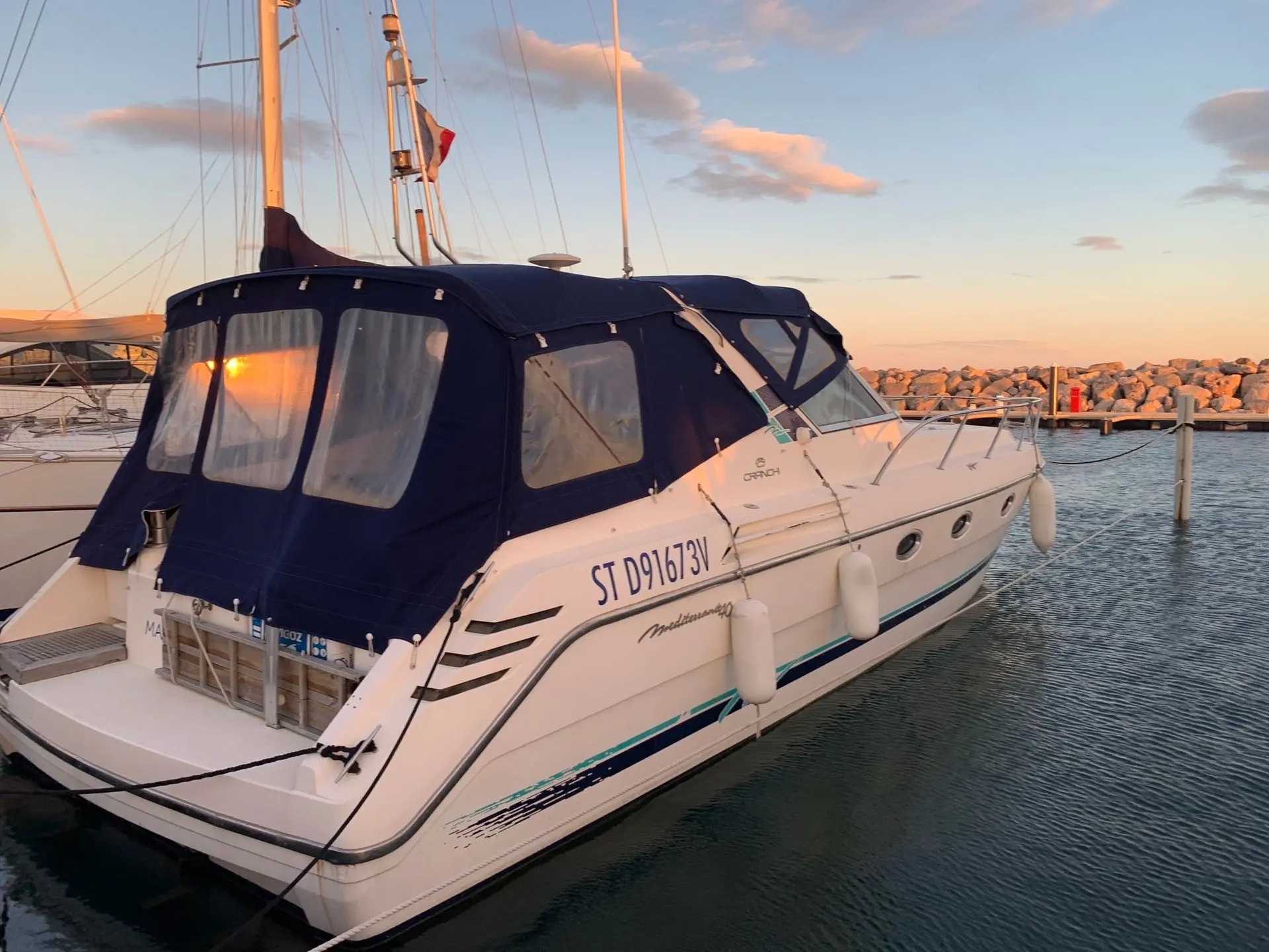 Cranchi Mediterranee 40 — Bateau à moteur blanc amarré dans un port, vu de trois quarts arrière.