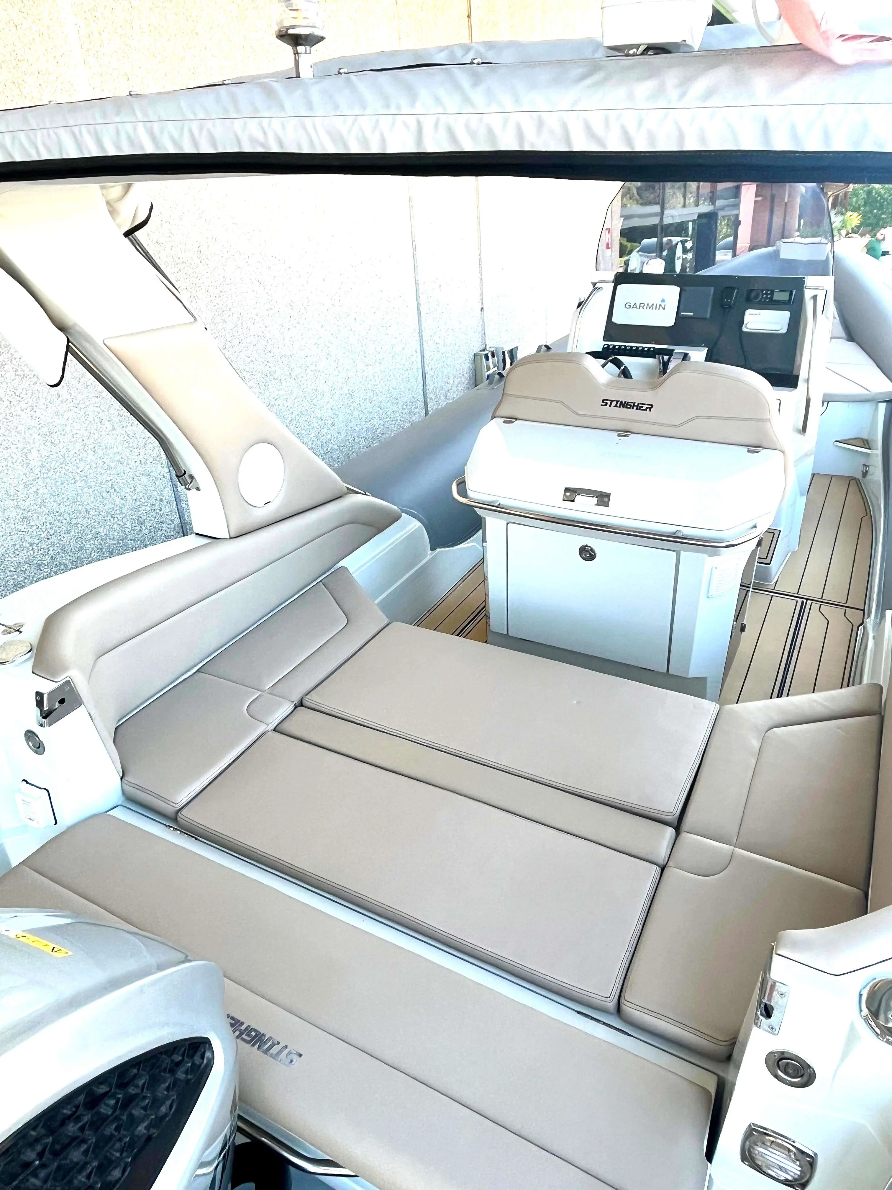 Italboats Stingher 28 GT — Vue du cockpit avec banquettes, console de pilotage et coussins de bain de soleil.