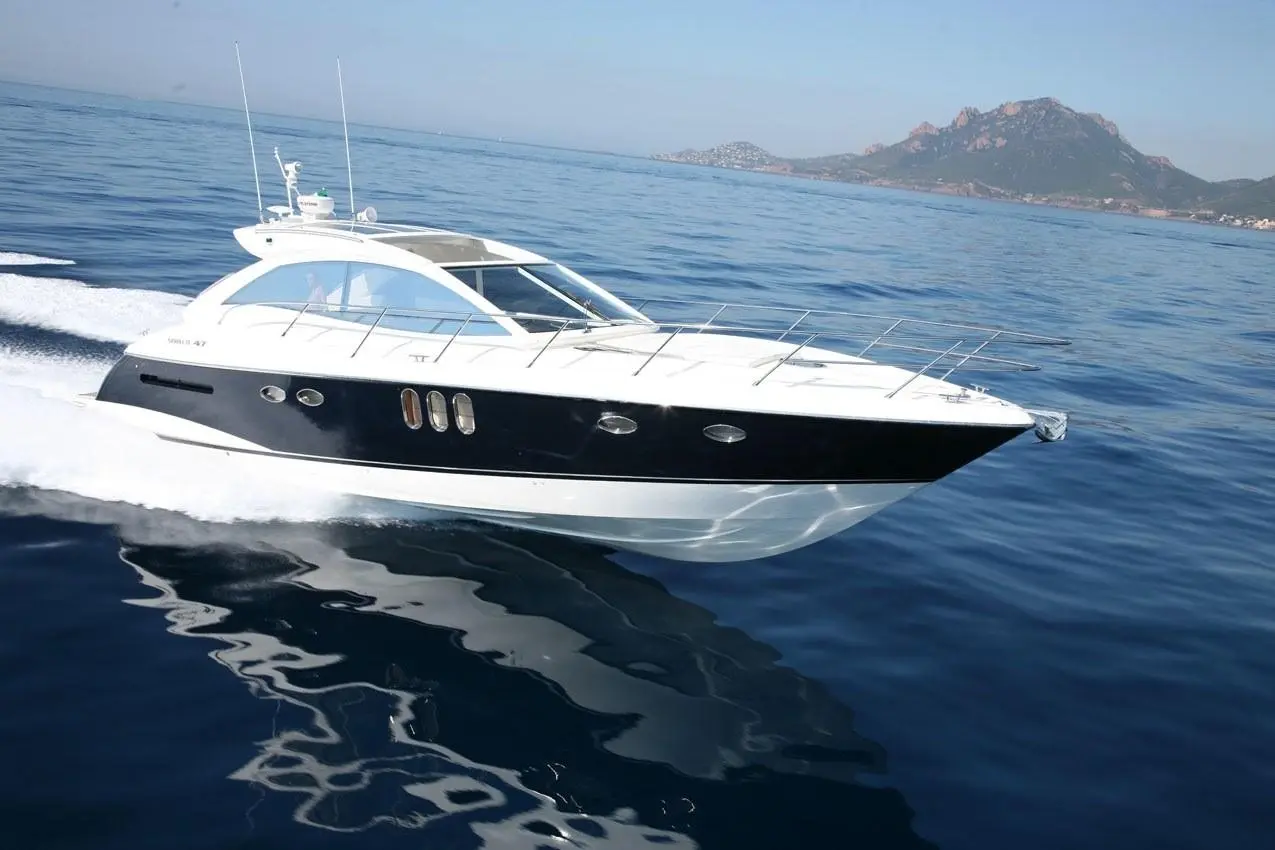 Absolute 47 — Vedette à moteur blanche et noire naviguant en mer devant une côte montagneuse.