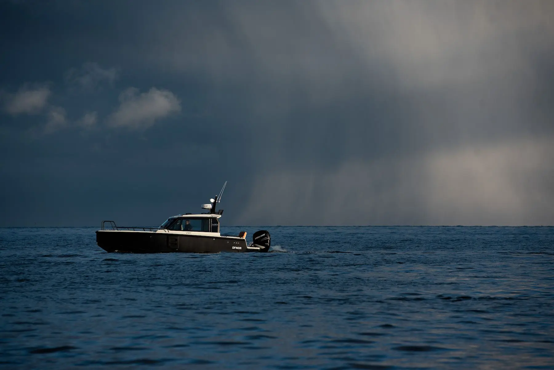 XO Boats DFNDR 8 — Bateau à moteur vu de profil naviguant en mer sous un ciel nuageux.