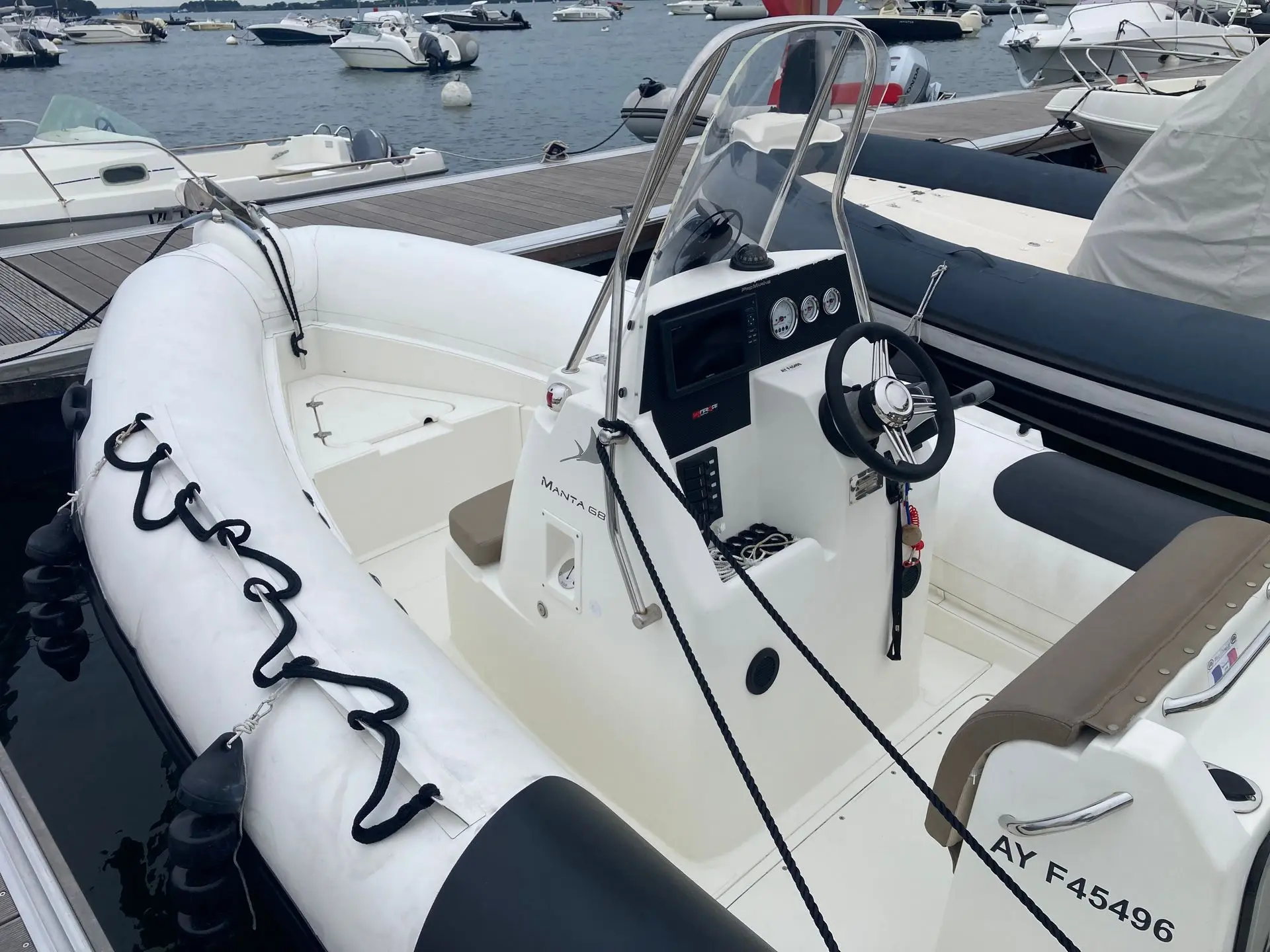 Pro Marine Manta 680 — Vue rapprochée du poste de pilotage et du pont d’un semi-rigide amarré au port.